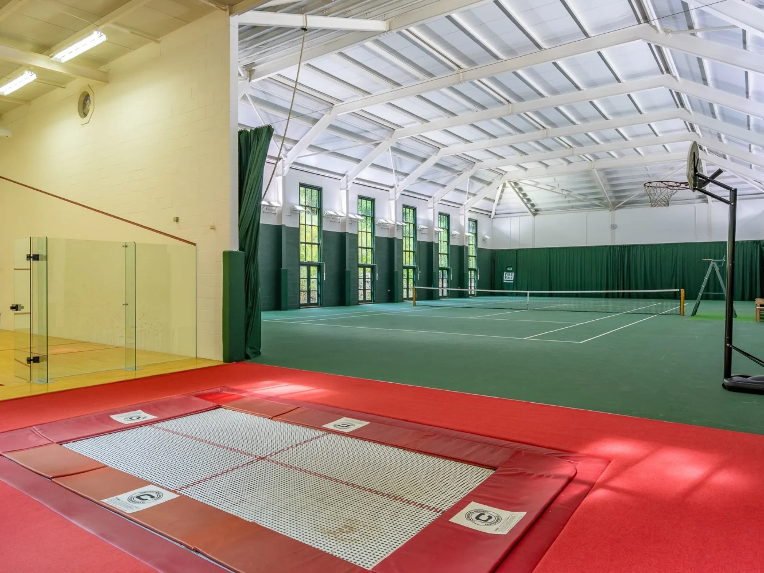Green indoor tennis court and red trampoline area