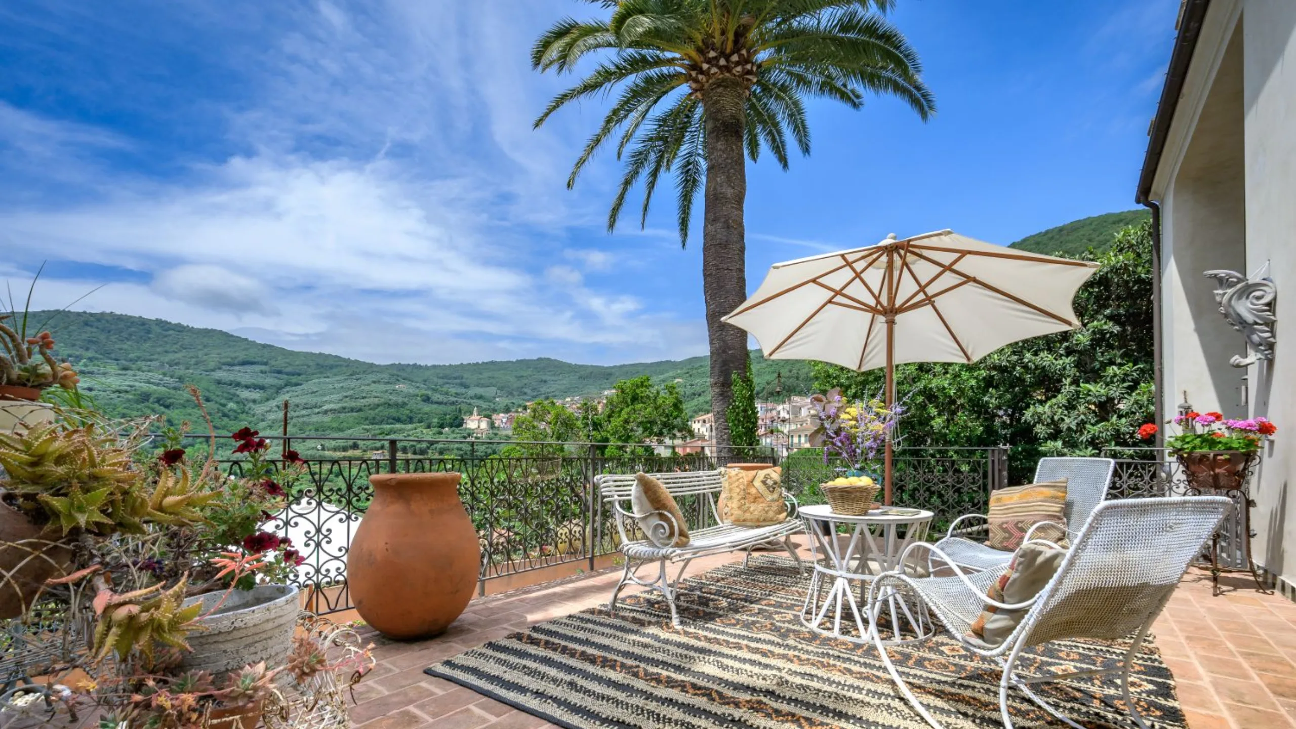 Terrace with dinning table and chairs with a parasol overlooking rolling green hills