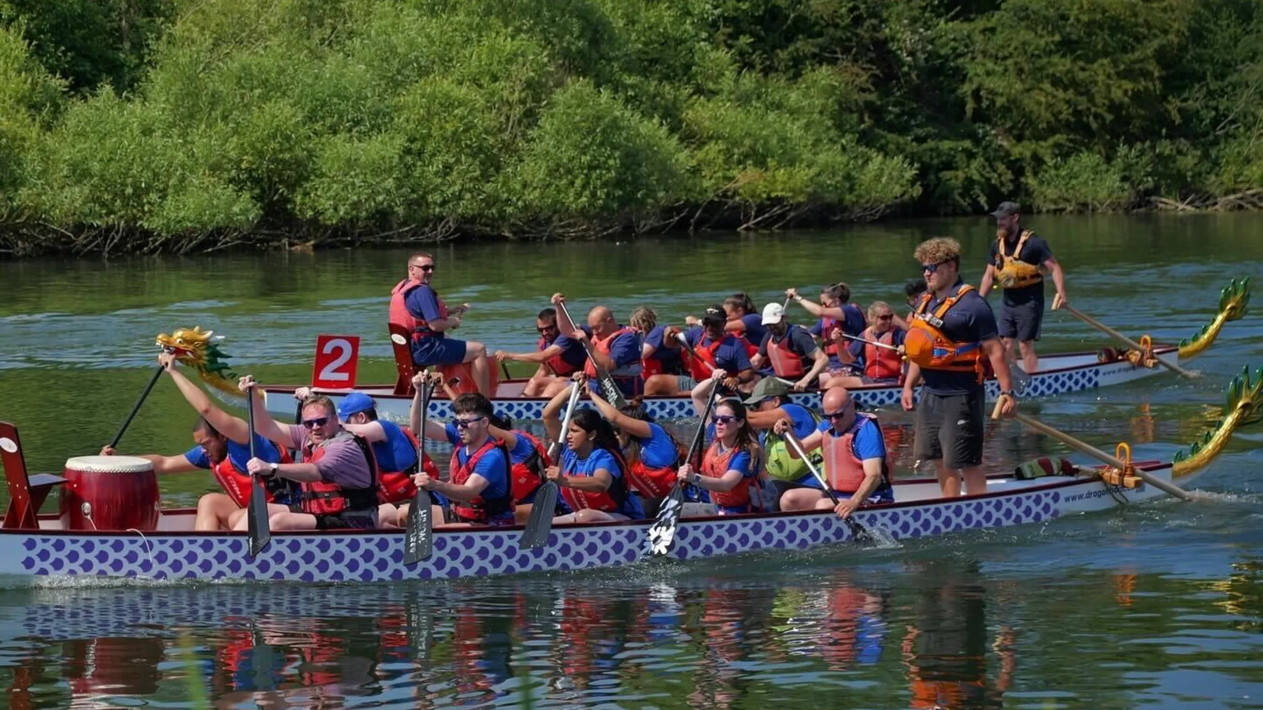 Two teams of people competing in a dragon boat race on a river