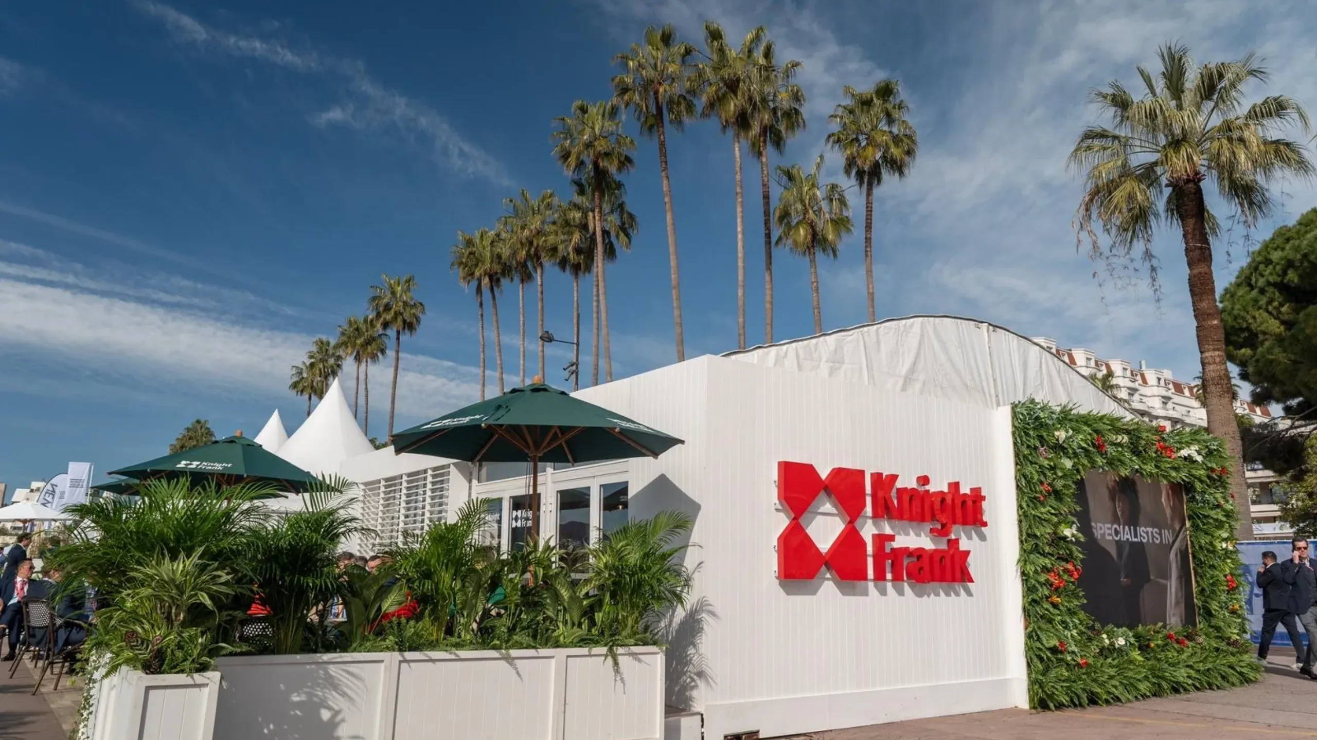 white-tent-with-knight-frank-logo-surrounded-by-tall-trees-and-flower-boxes