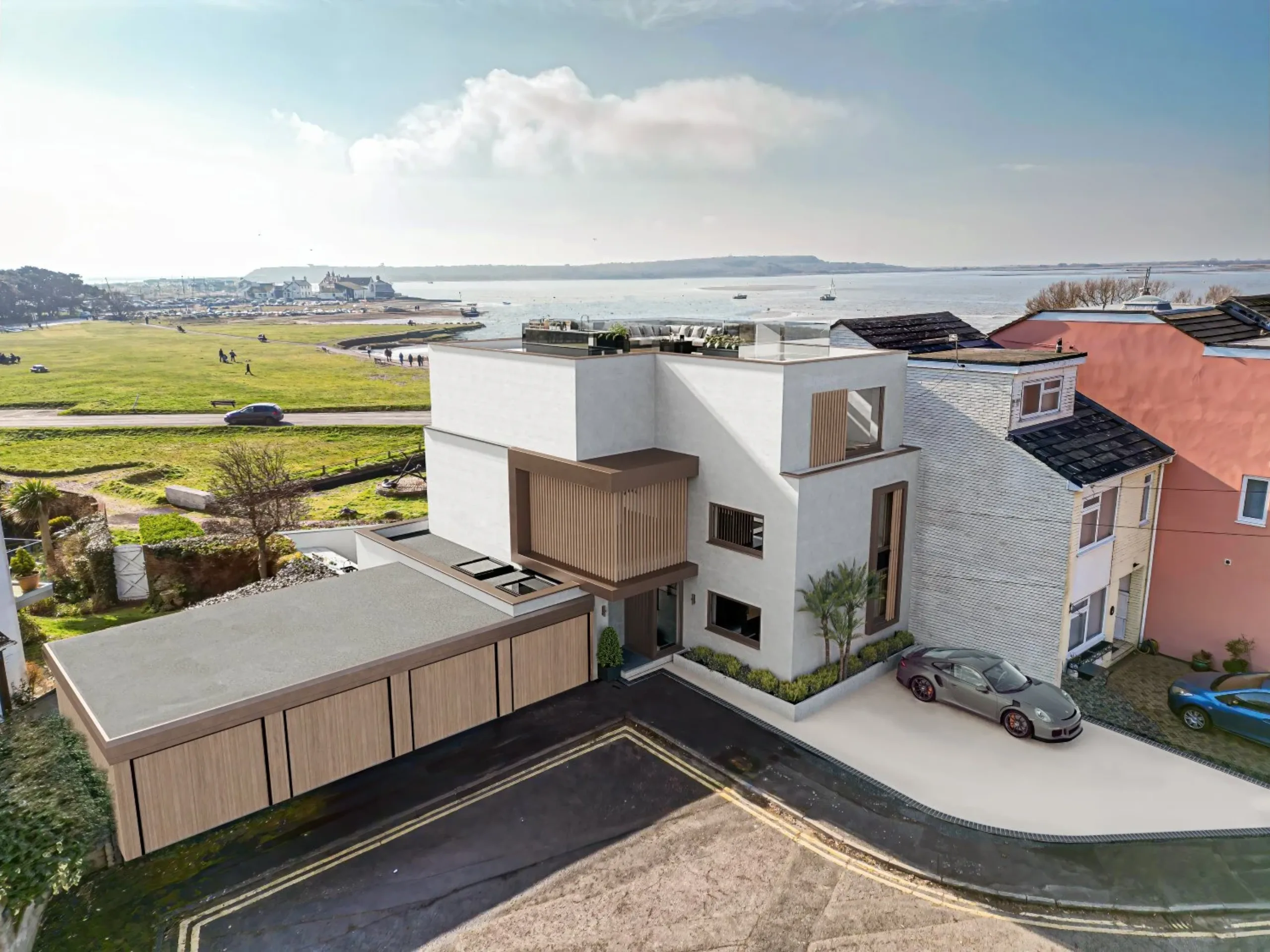 Ariel shot of the exterior of a contemporary home with grass fields in the background, under a blue sky