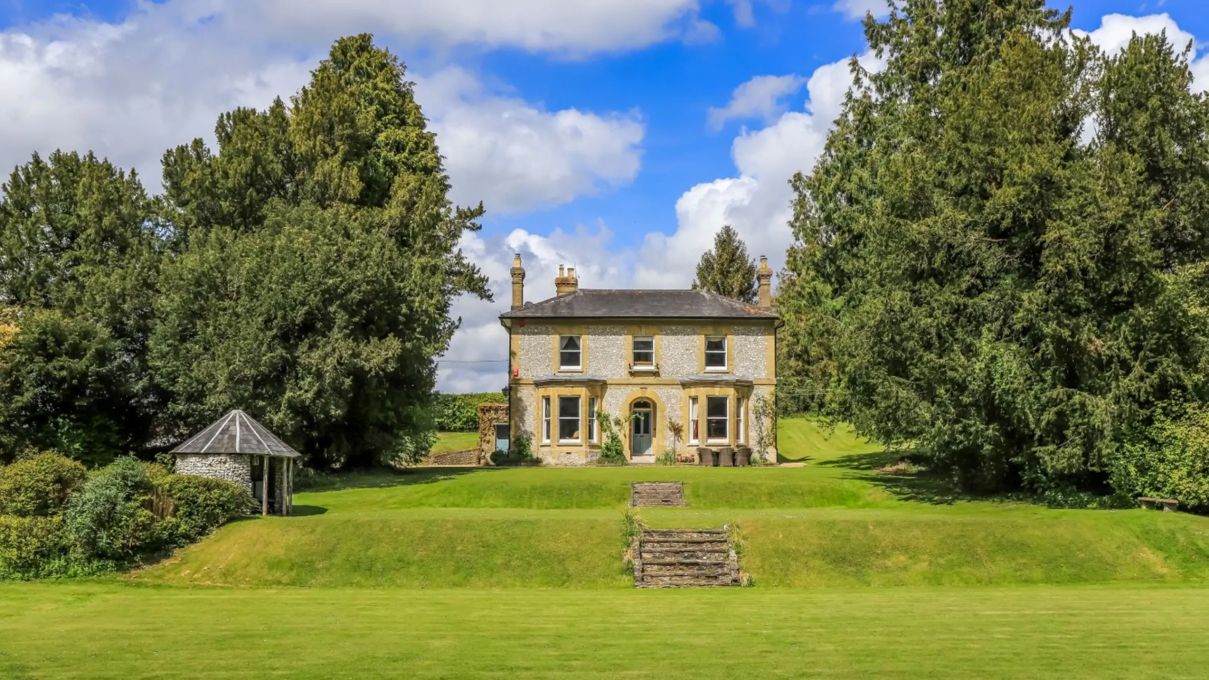Country house exterior surrounded by green garden and trees