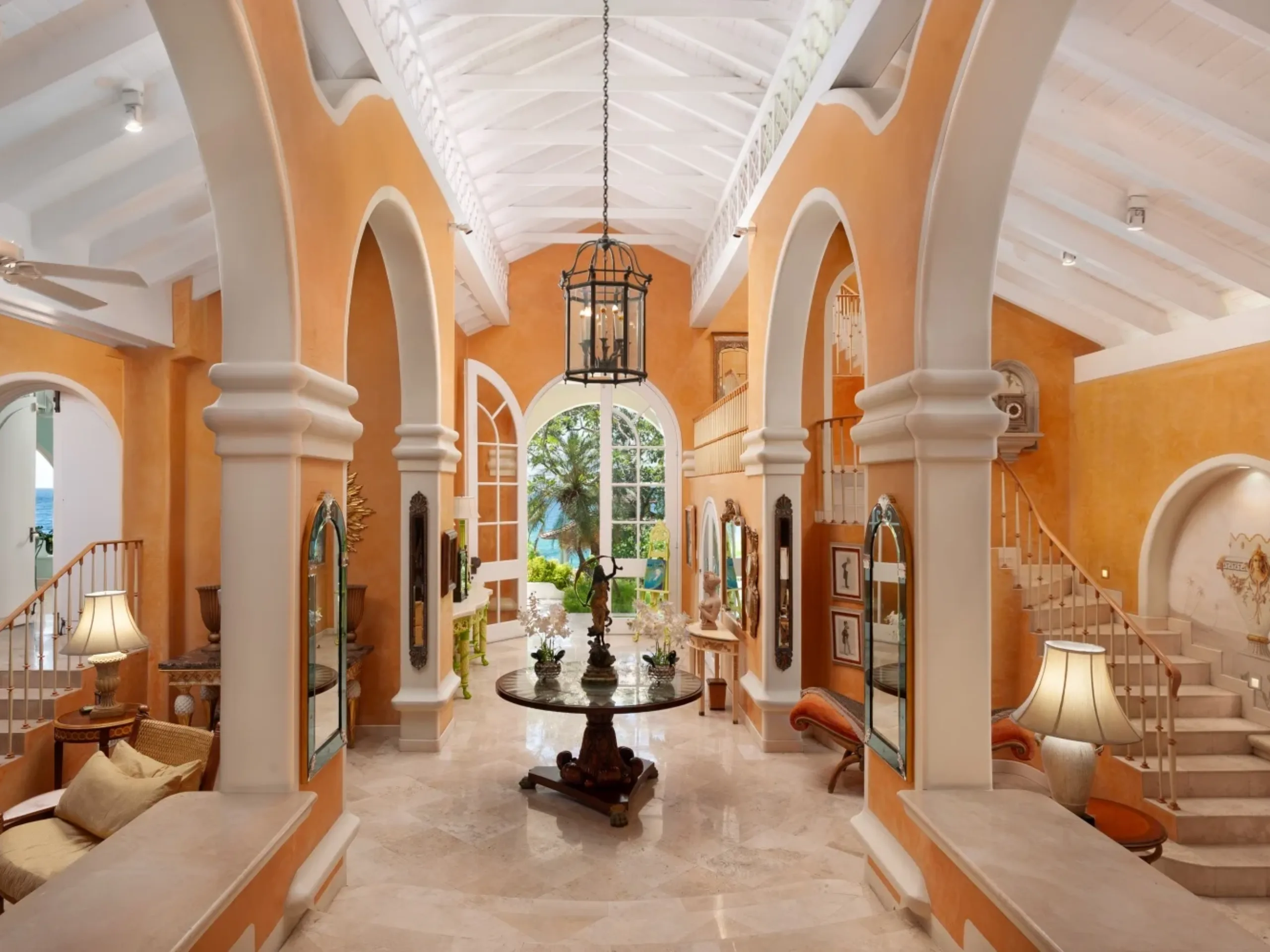 grand orange lobby with a double staircase, marble flooring with a large table in the center