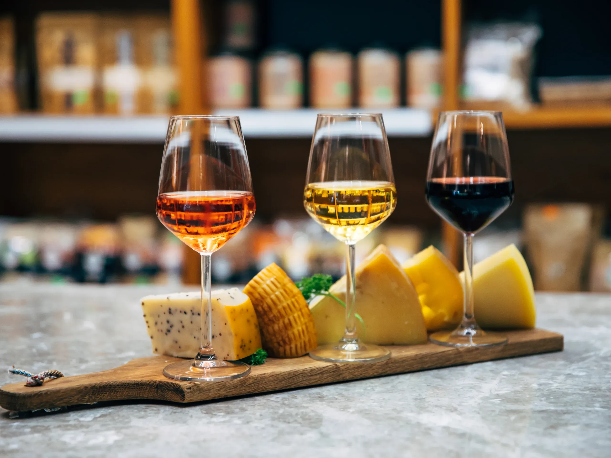 Glasses of wine, with a selection of cheeses on a board. 