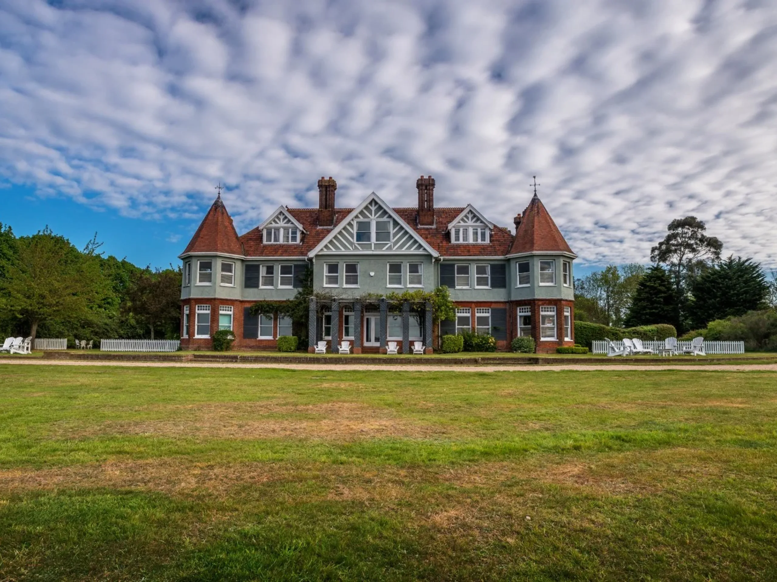 Exterior of a large home surrounded by trees and large green garden