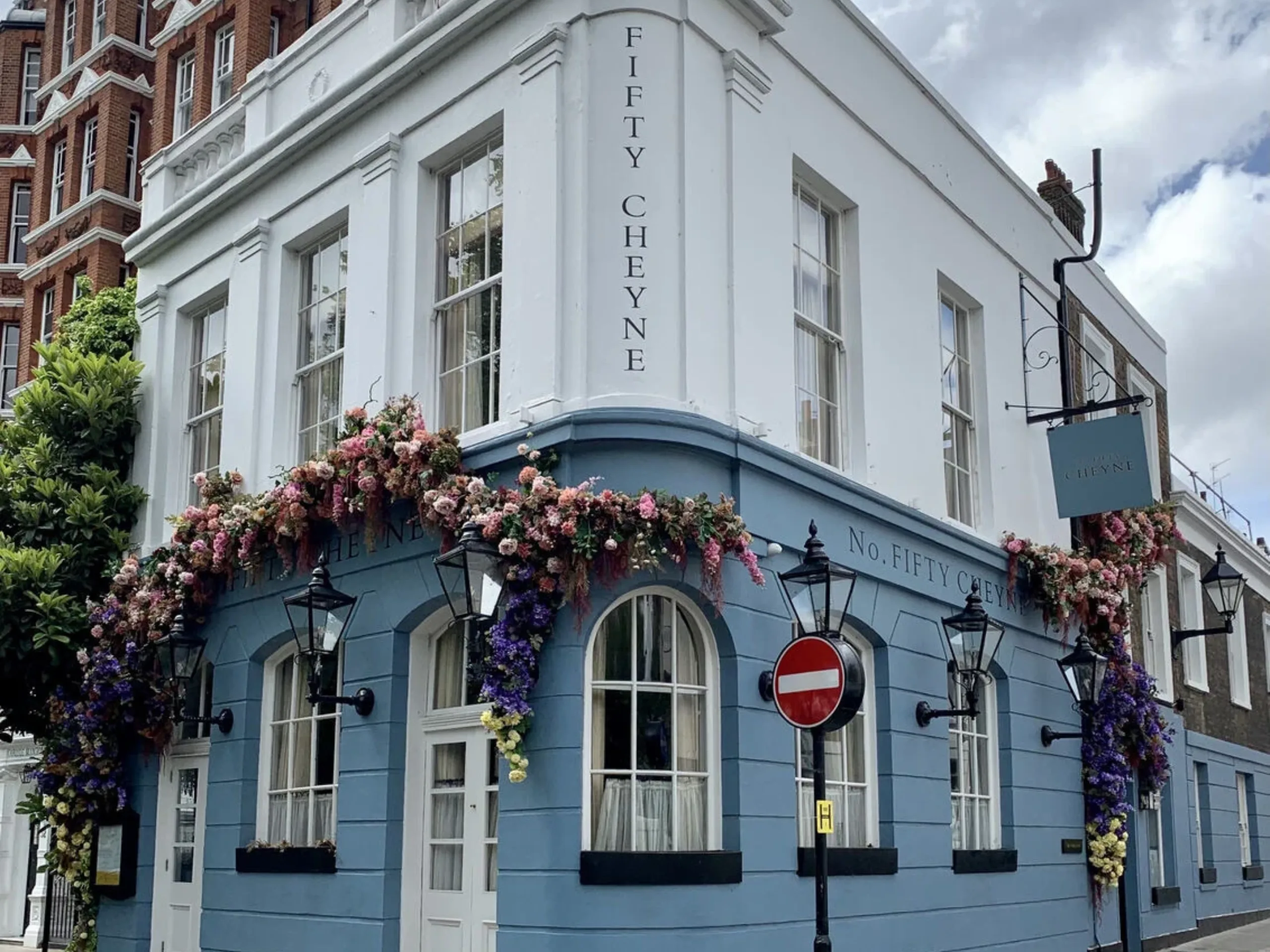 Exterior of a blue and white pub building with flowers growing on the wall