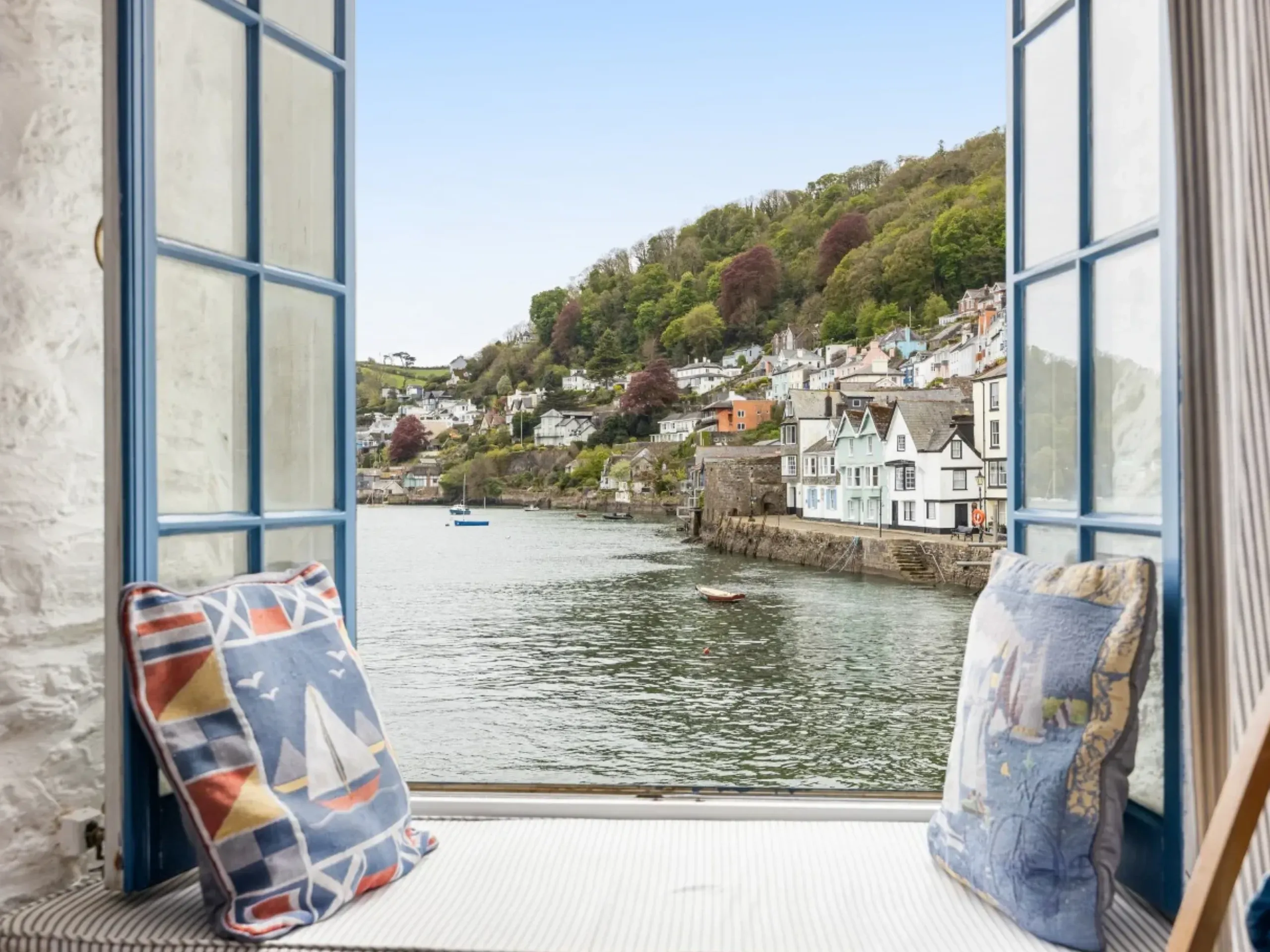 window seat with open window looking out to the water with boats and houses in the background