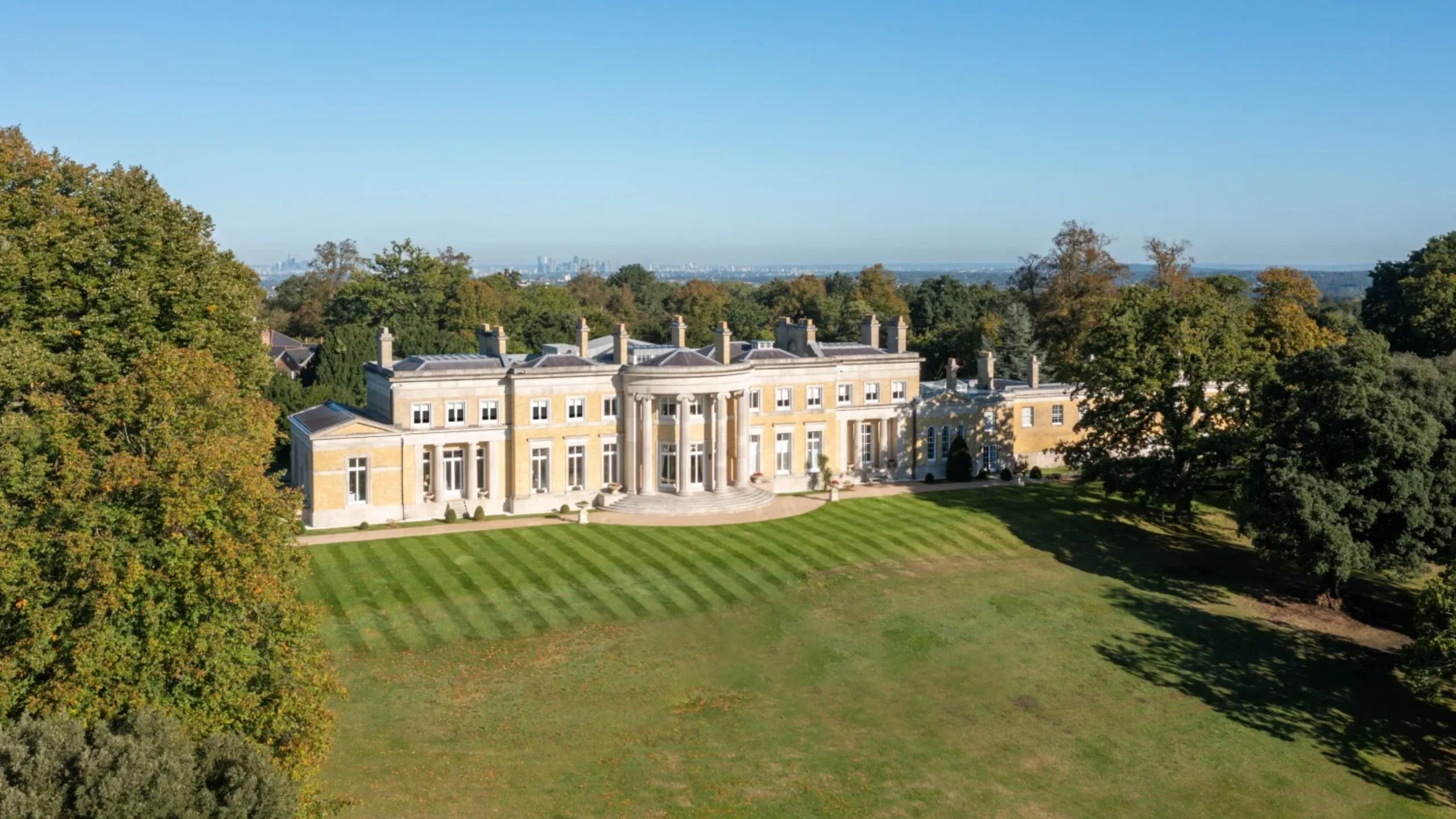 Large stately home surrounded by a large lawn and trees