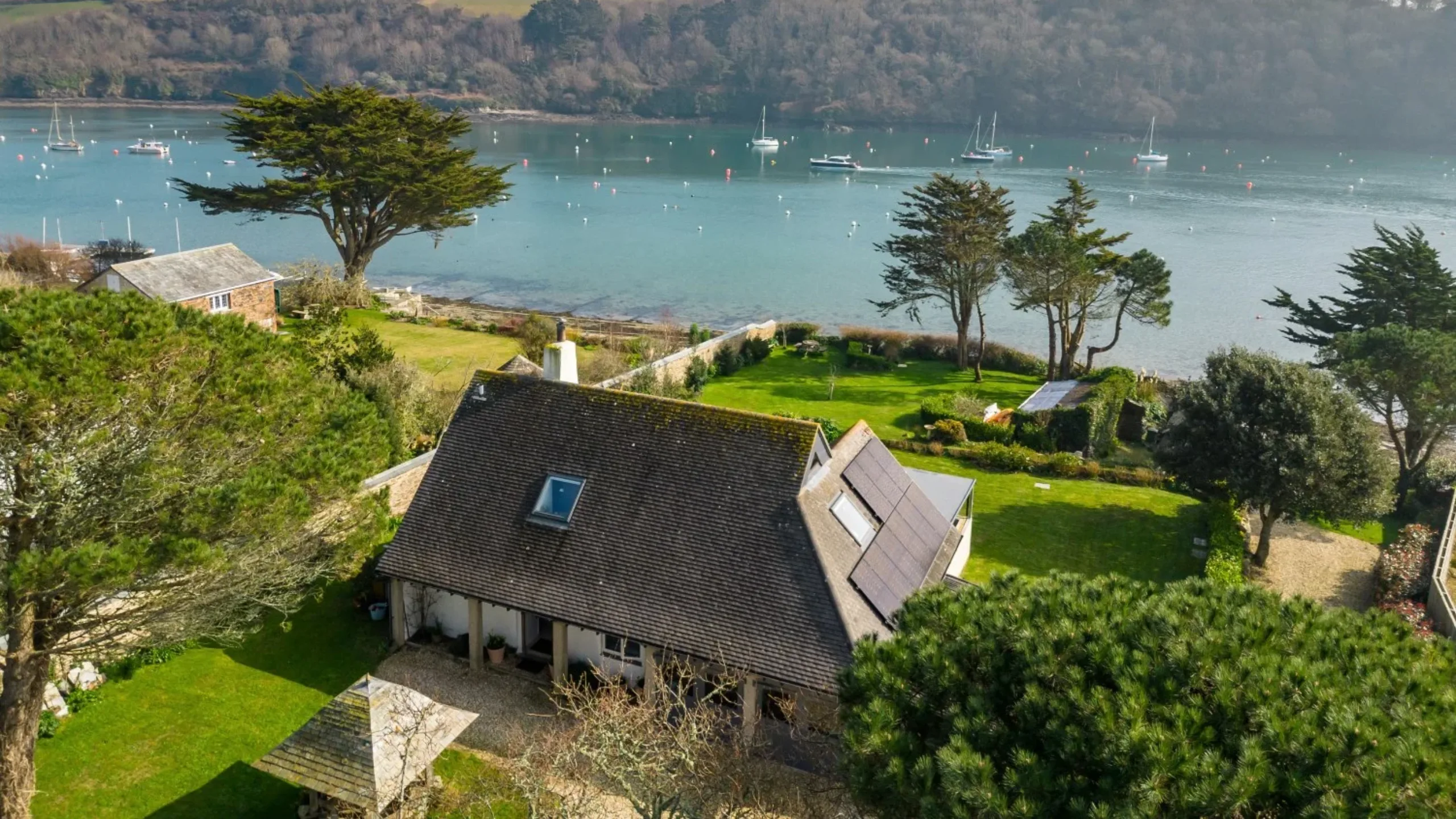 Ariel shot of house exterior surrounded by gardens and with a lake in the background
