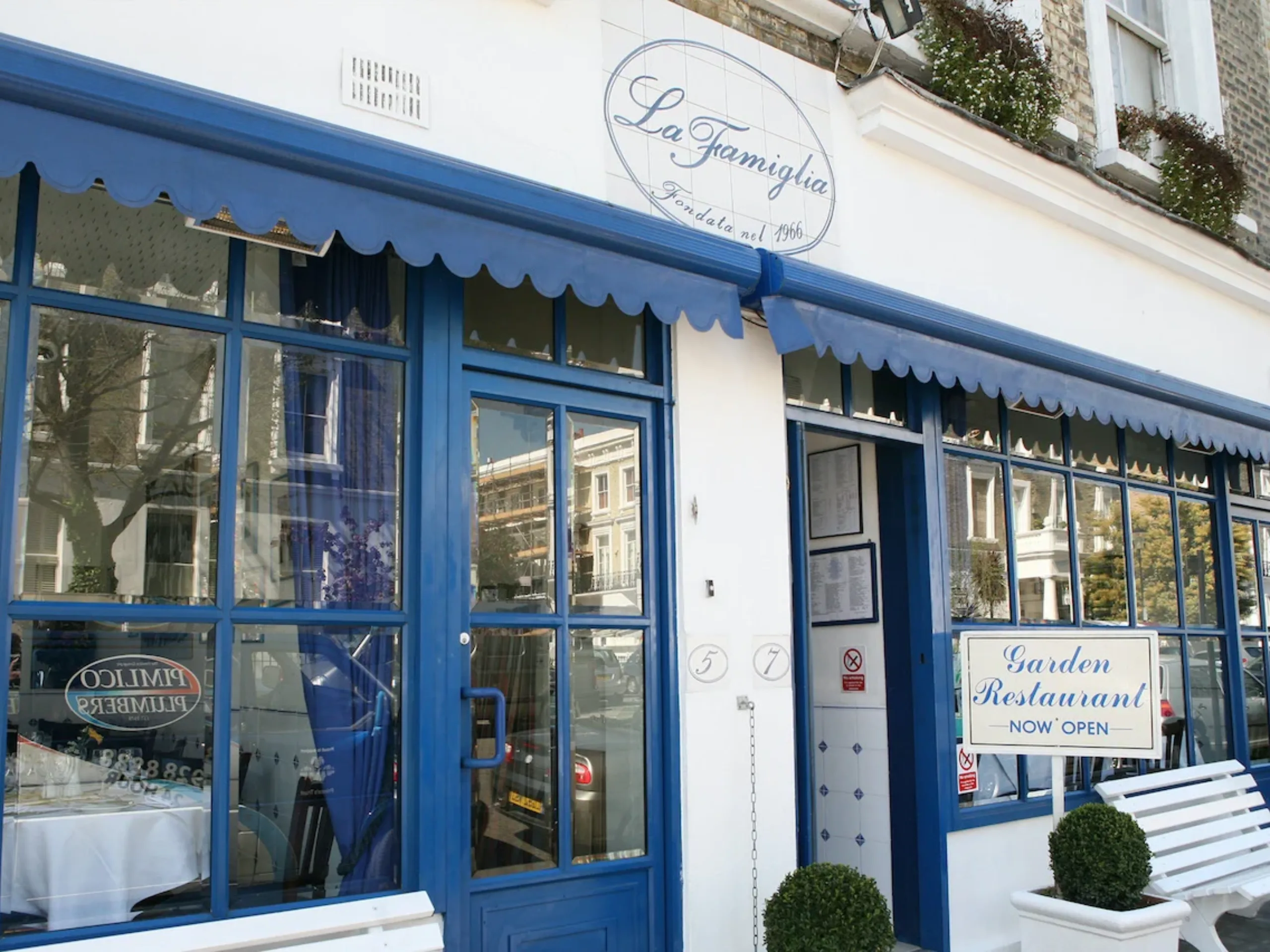exterior of restaurant with white walls and blue windows with a white bench outside