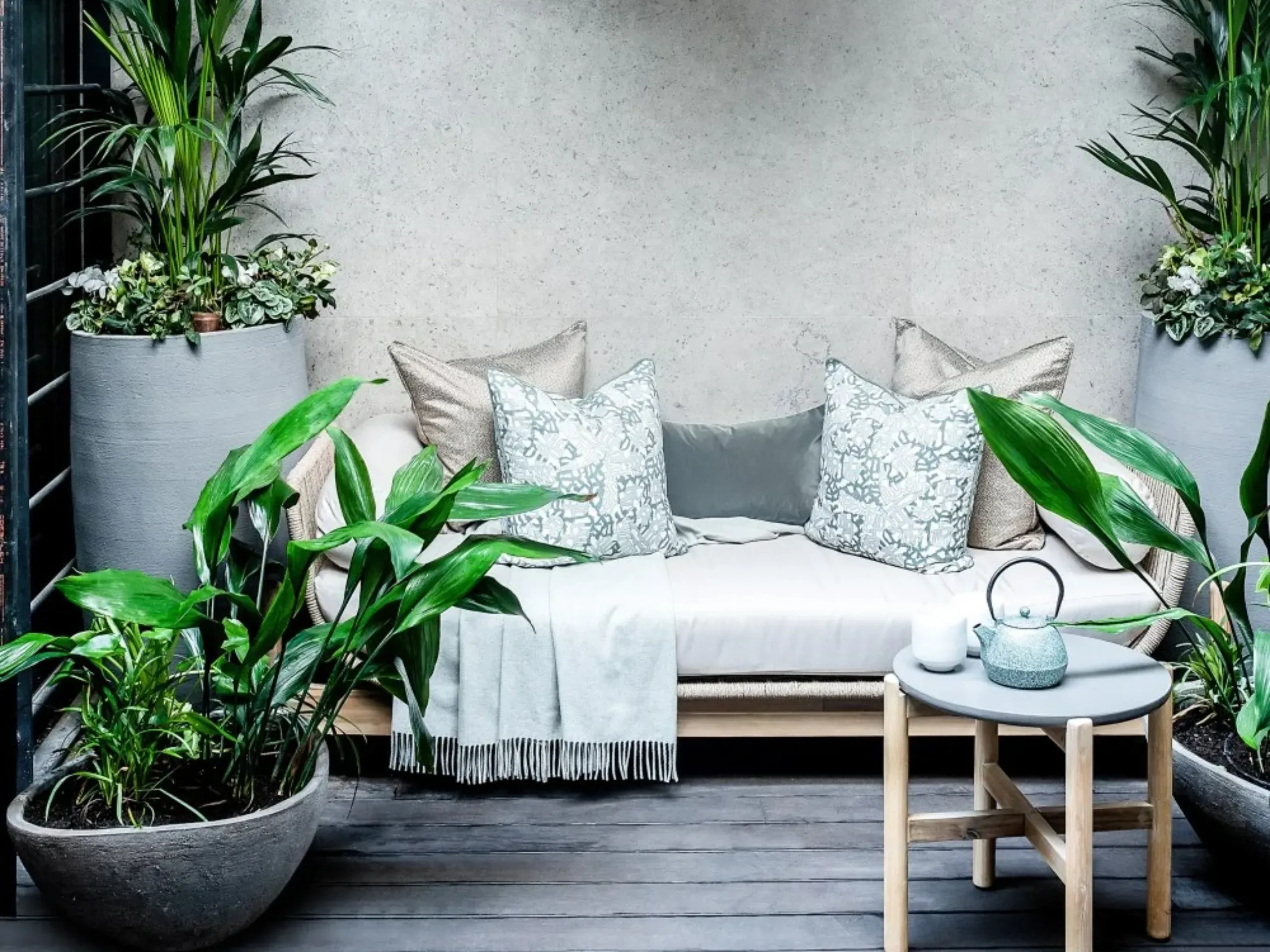 Garden loveseat surrounded by potted plants and with orb shaped hanging lights above