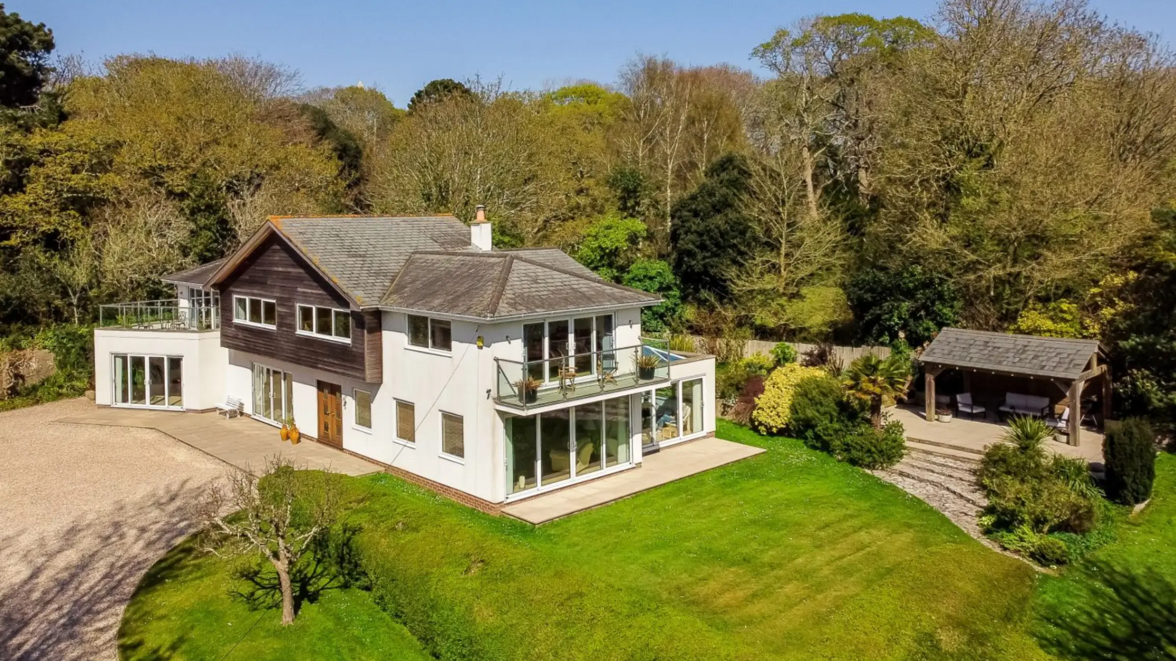 Exterior of white walled house and the garden with trees in the background