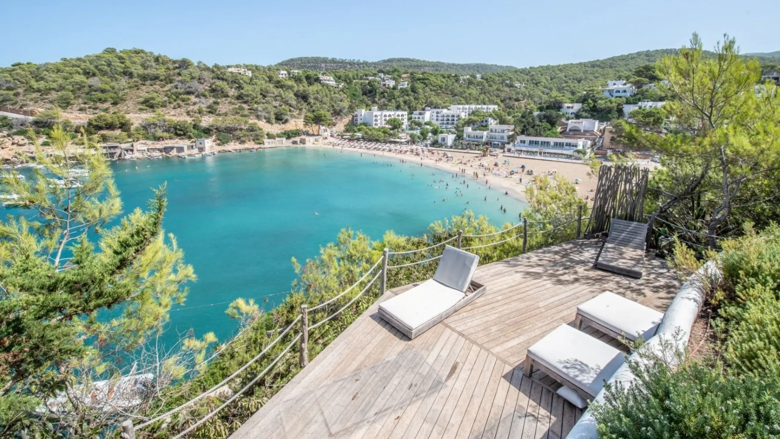Decking with sun loungers overlooking a beach with mountains in the background