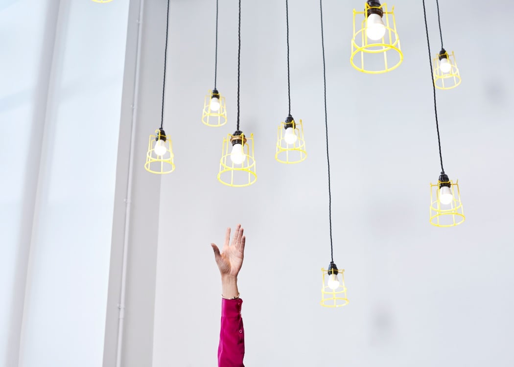 A hand reaching for lightbulbs