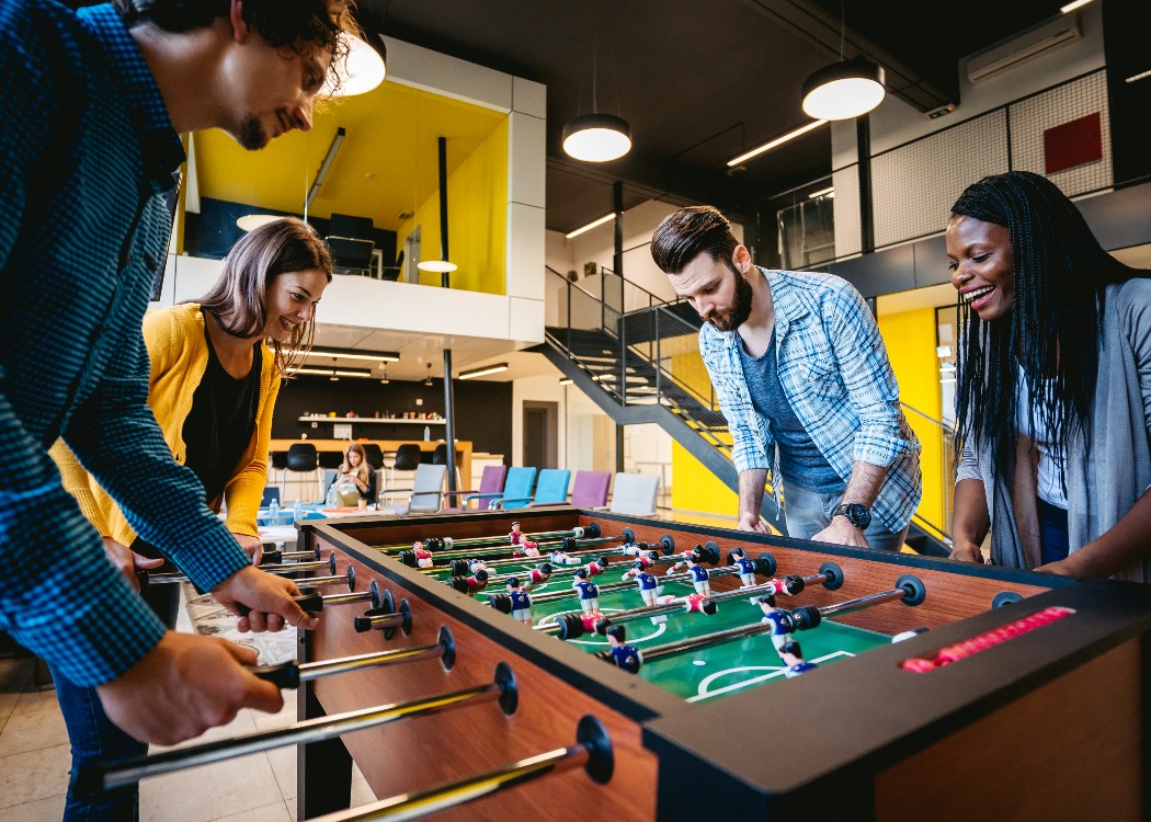 Coworkers playing table football in breakout space