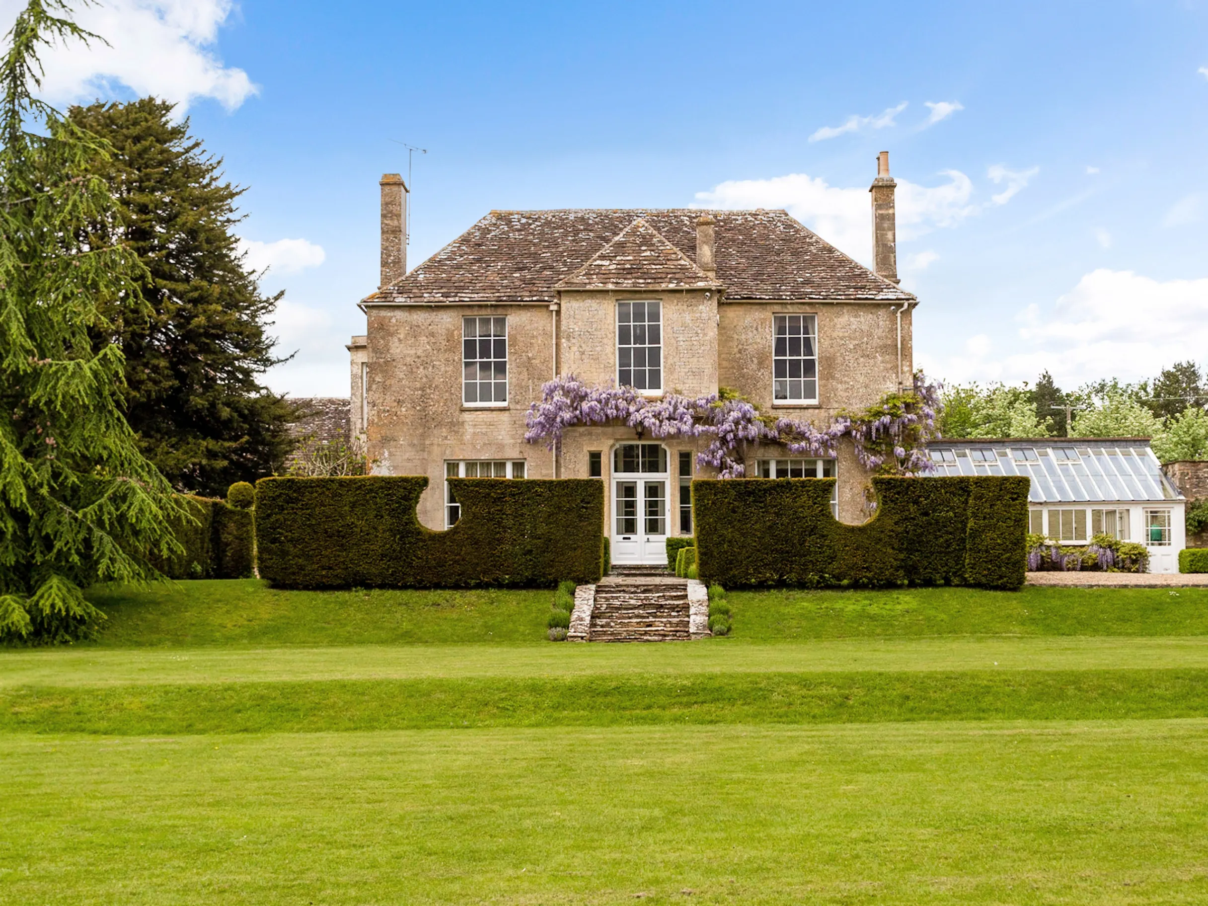 Exterior of country home in the background and large green garden in the foreground