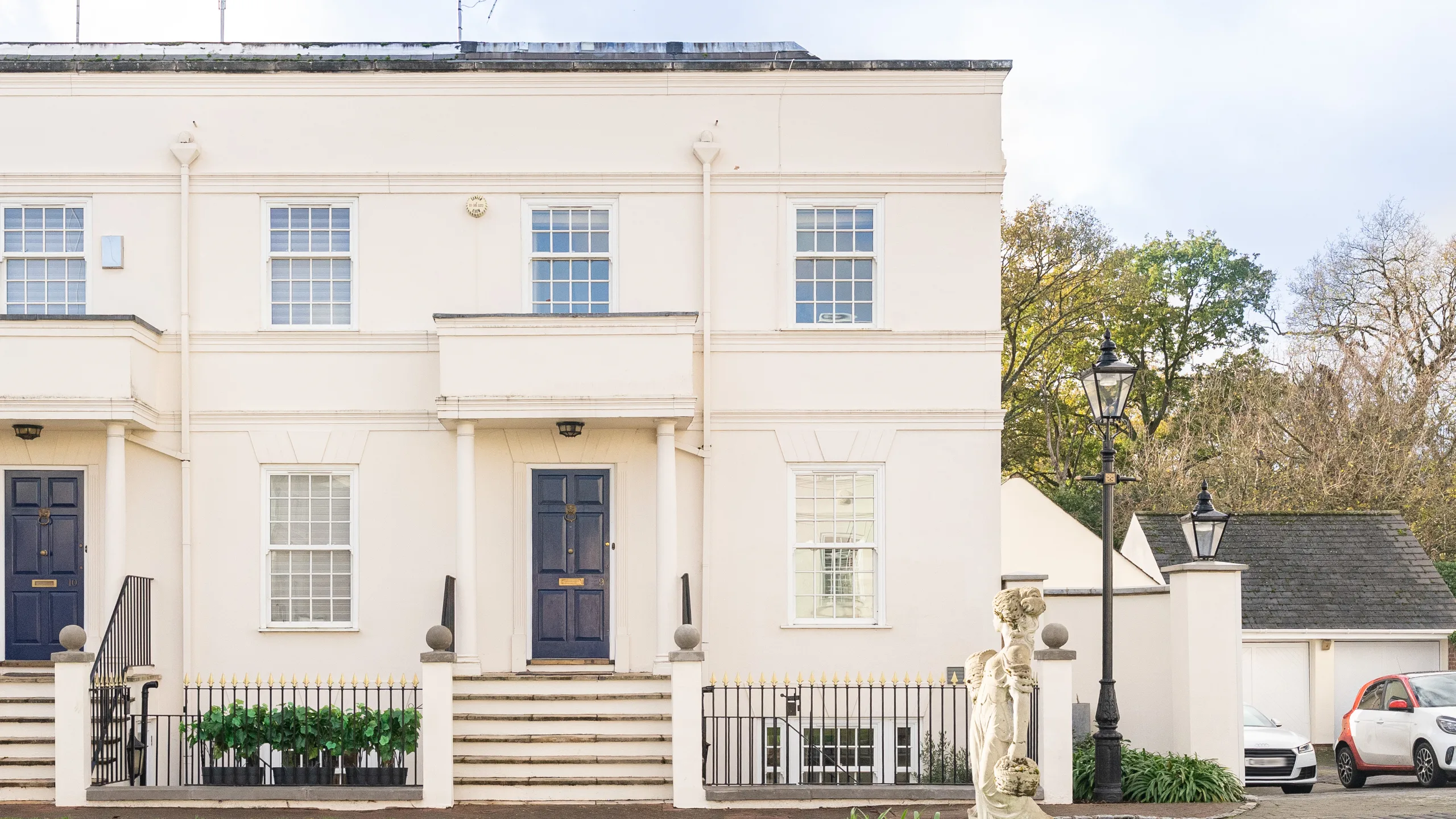 Exterior of a white end-of-terrace Georgian house with a statue at the front