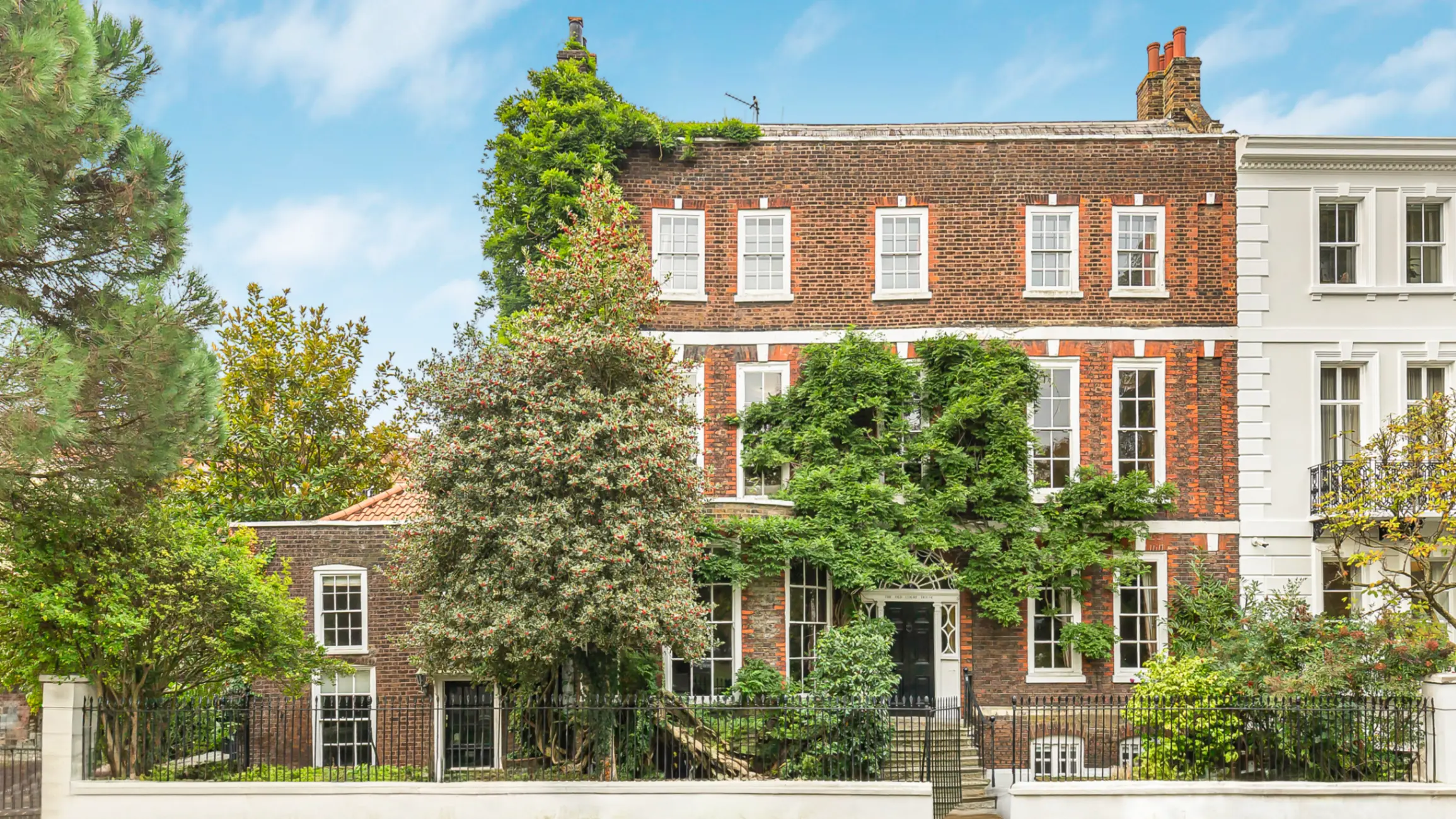 Grade II* listed Queen Anne property with mature trees in front 