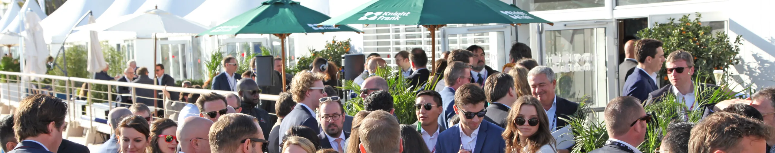 group-of-people-in-suits-standing-in-front-of-white-gazebos-and-green-umbrellas