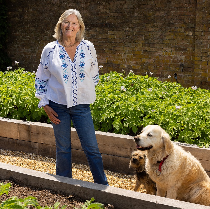 A woman walking in a garden with two dogs