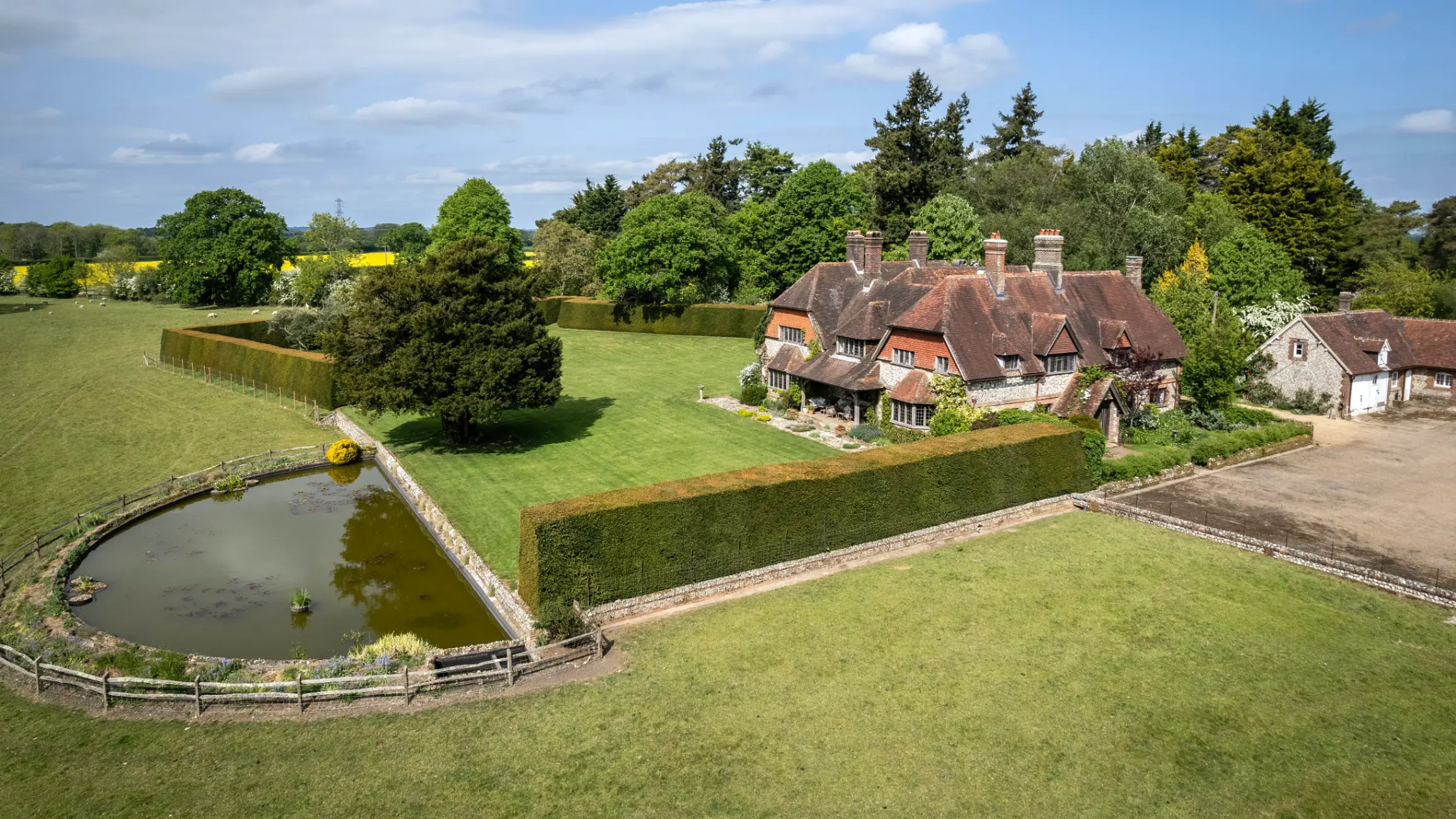 exterior-of-period-country-home-with-large-green-gardens-with-a-pond-to-the-front