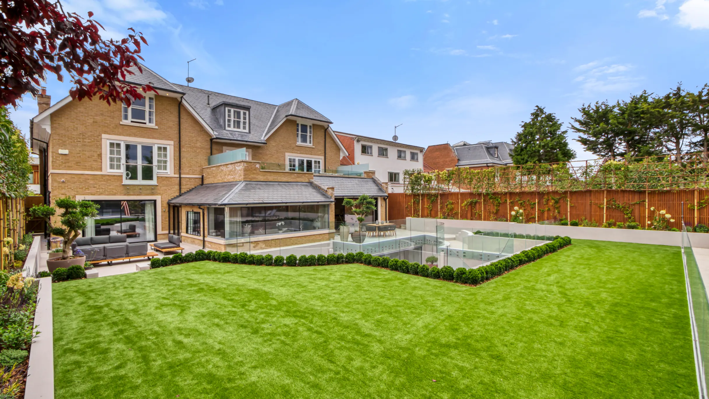 Exterior of a brown brick house with garden patio and large lawn 