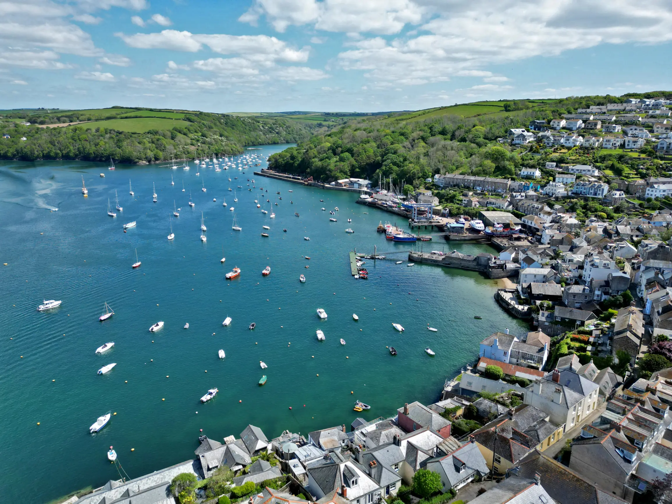 Ariel view of Cornish townhouses looking out to the harbour with lots of small boats 