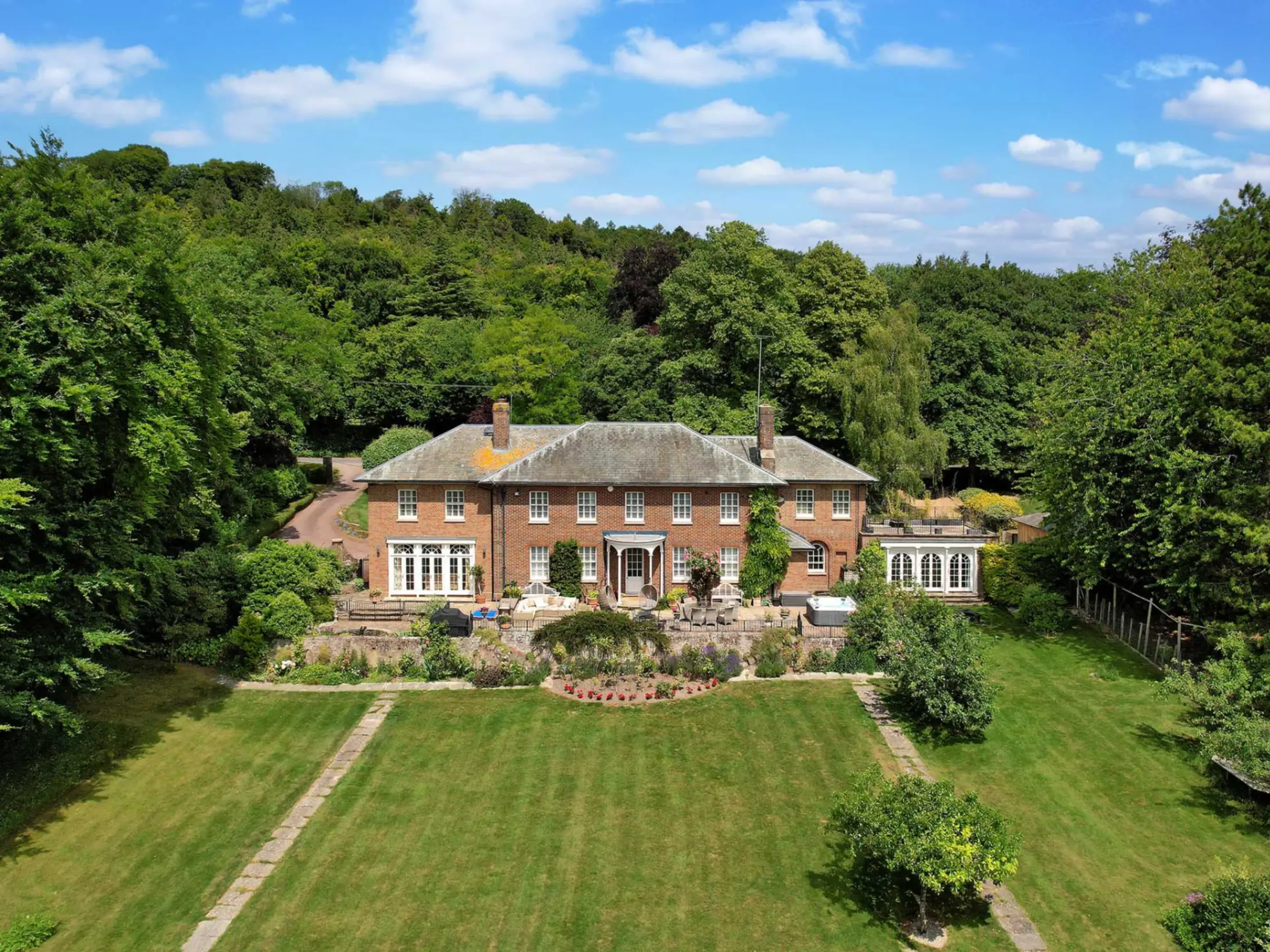 Large period country house, with a big garden in the foreground and mature trees to the side