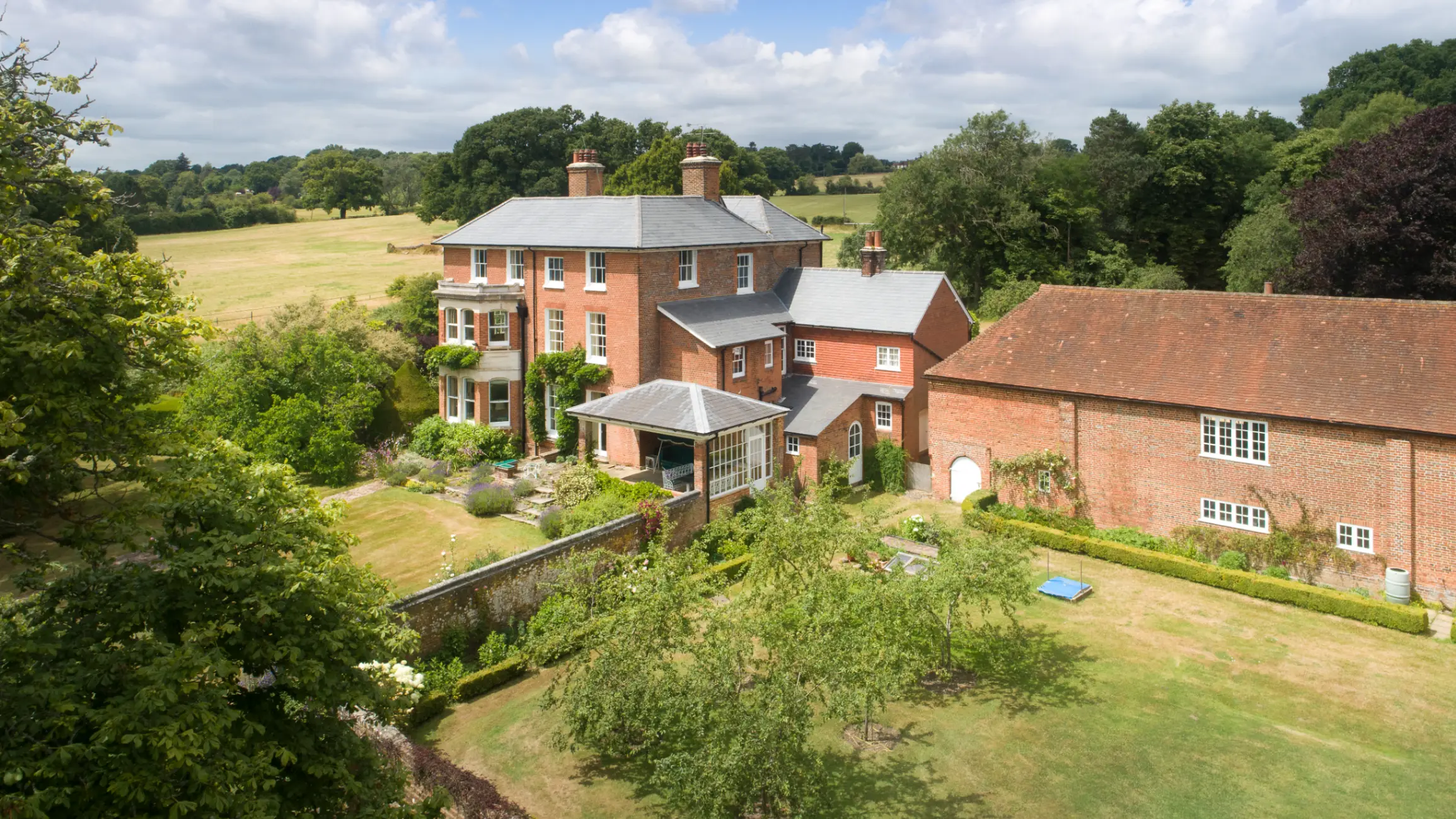 exterior-of-red-brick-large-country-home-surrounded-by-green-fields-and-mature-trees
