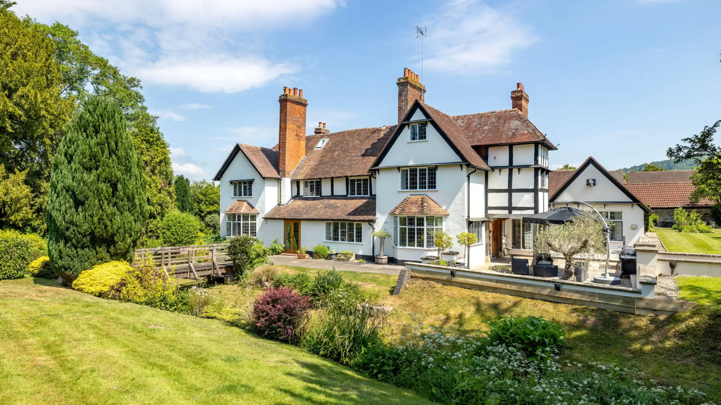 Exterior of a large country house with a big front garden with bushes and mature trees
