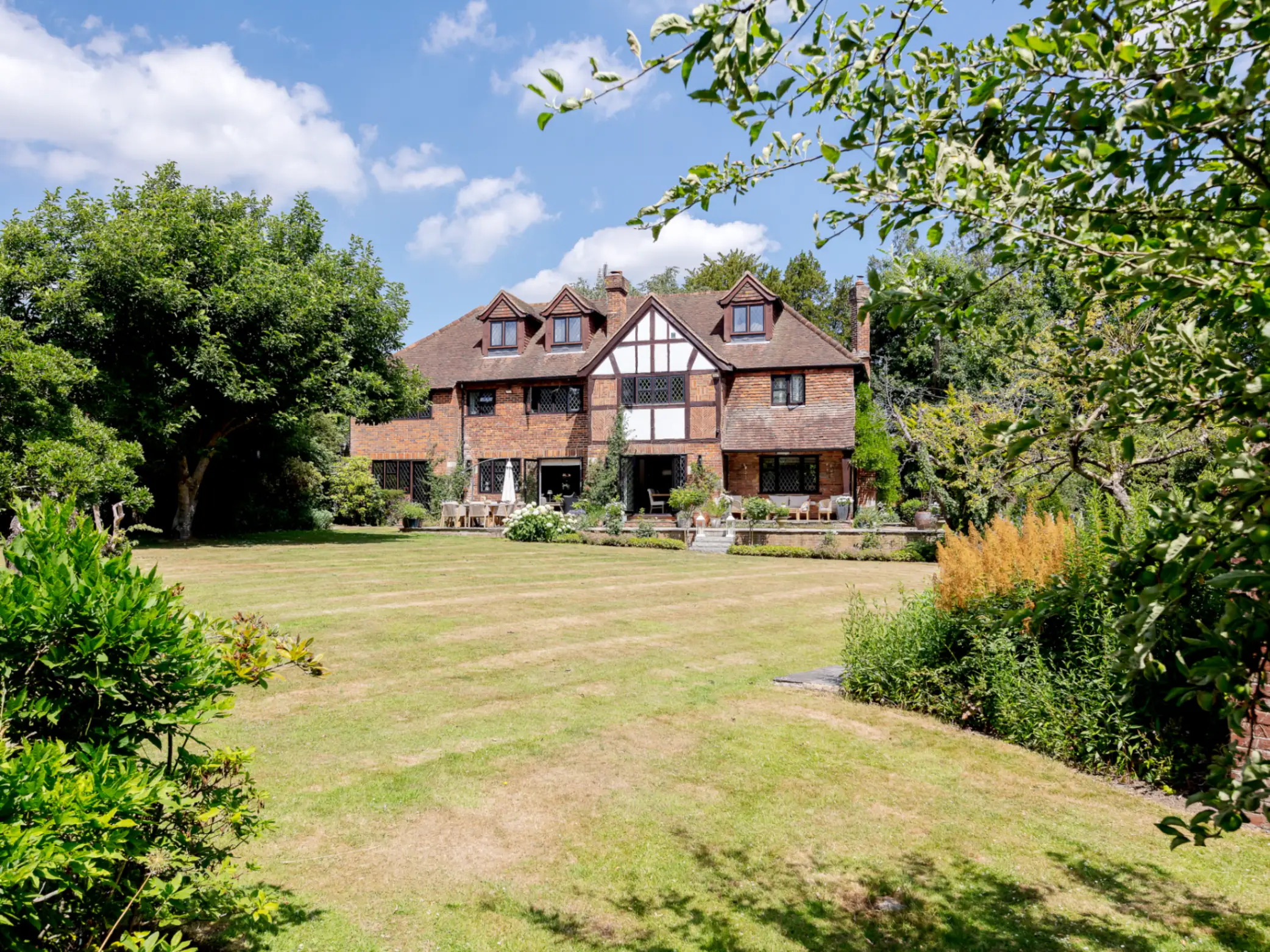 Exterior of period country house surrounded by a green lawn and mature trees 