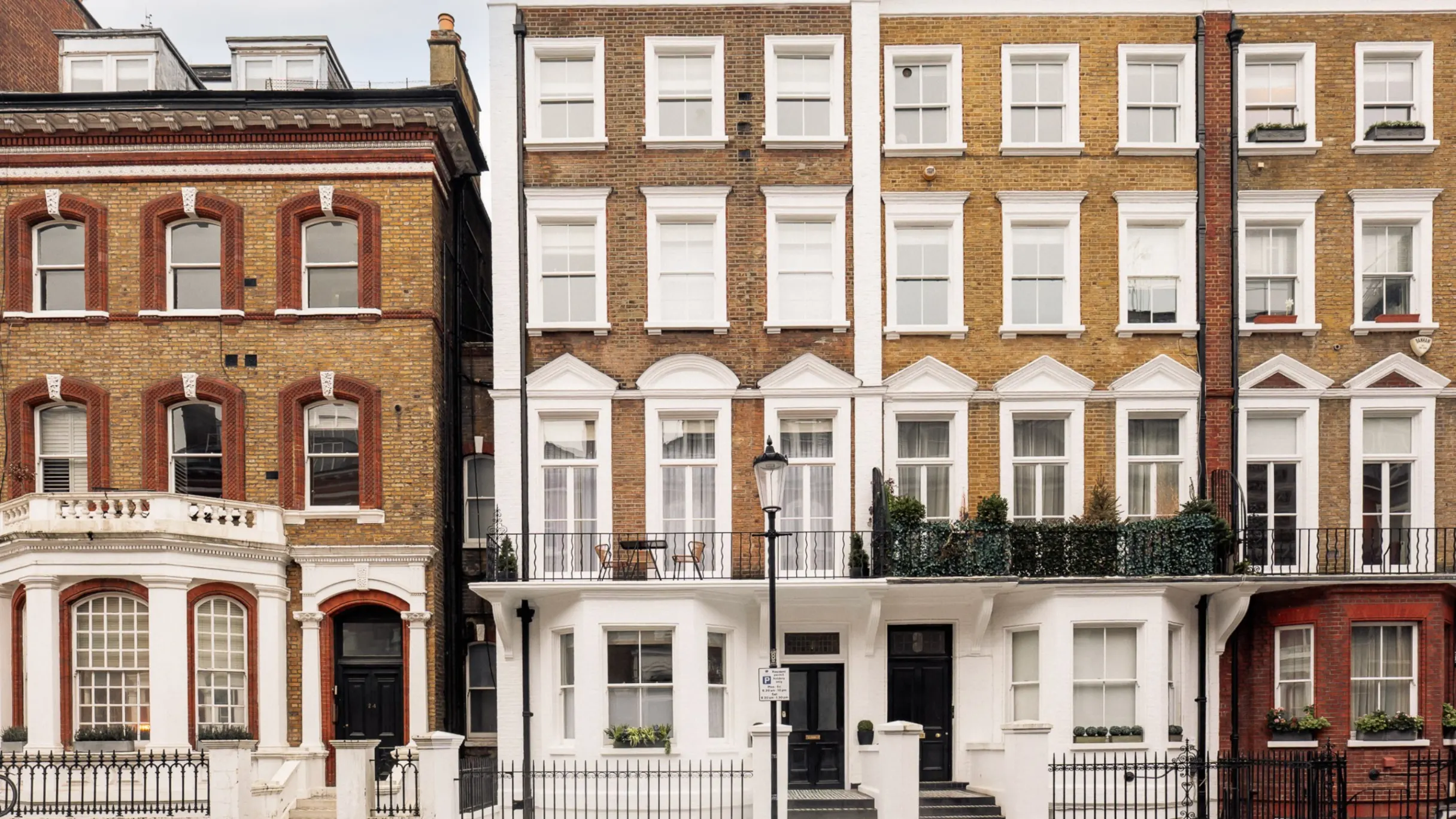 Exterior of a row of brown brick townhouses with balconies  
