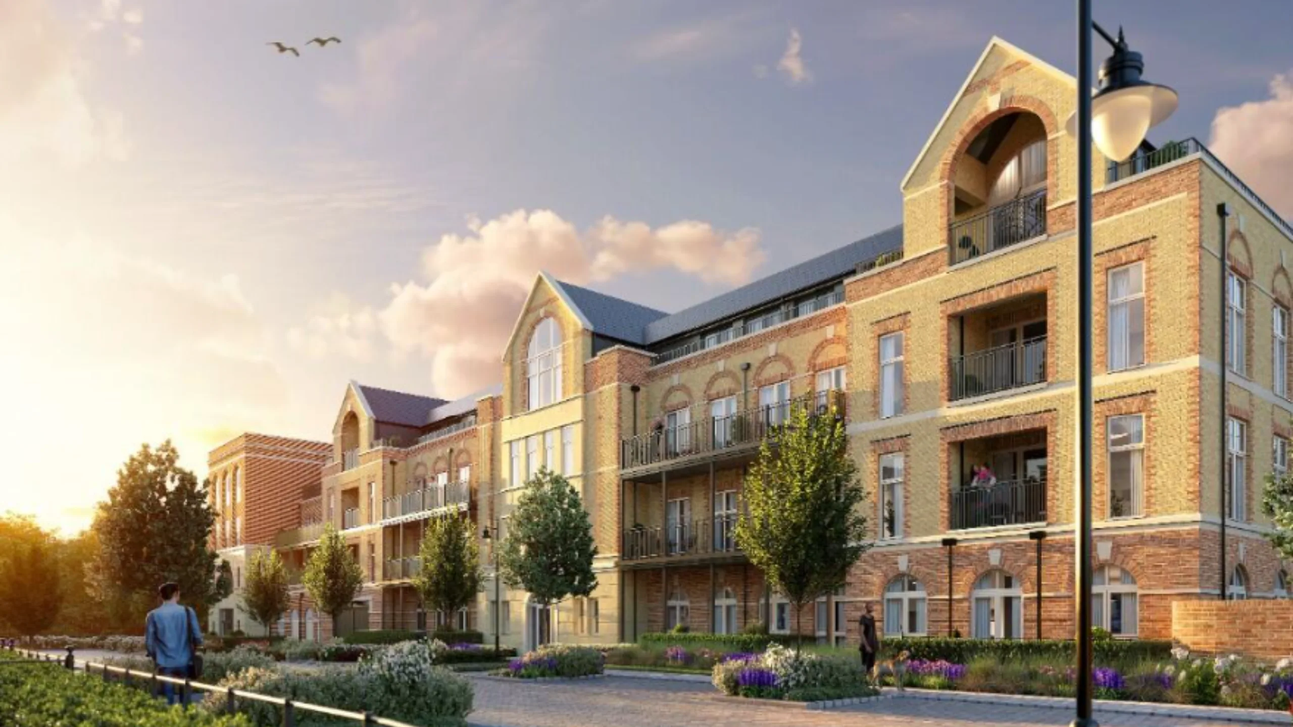 Exterior of a modern block of flats with trees and flower bushes in front 