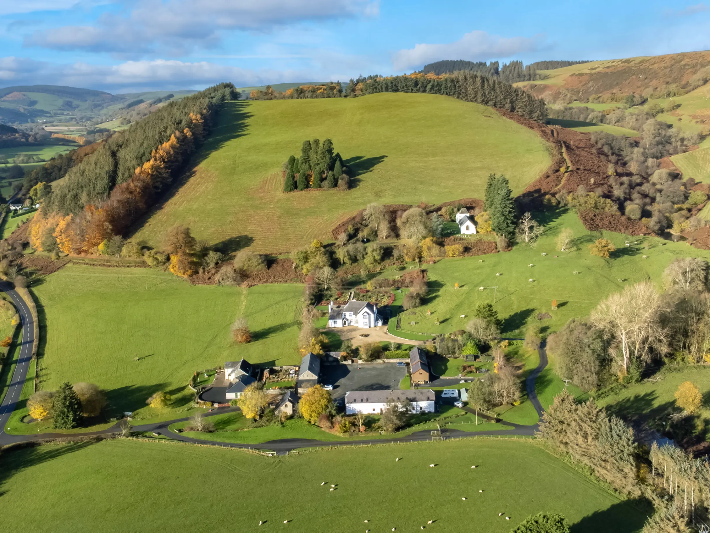 Ariel view of large county house surrounded by large green fields and trees