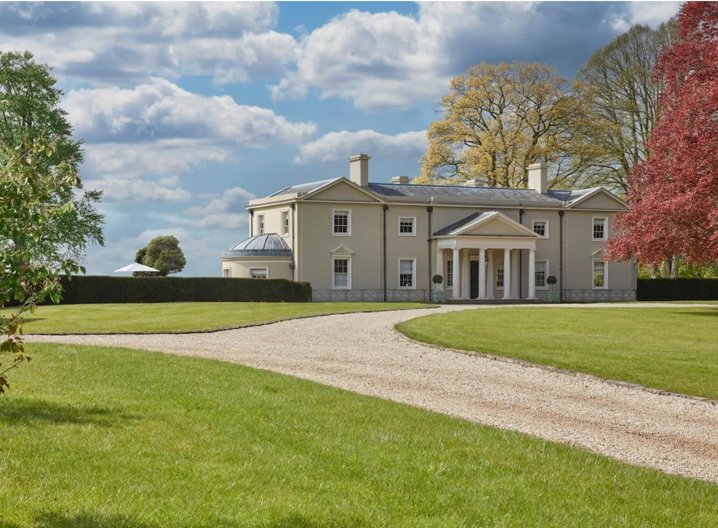 a photograph of a beautiful countryside manor home with a green lawn