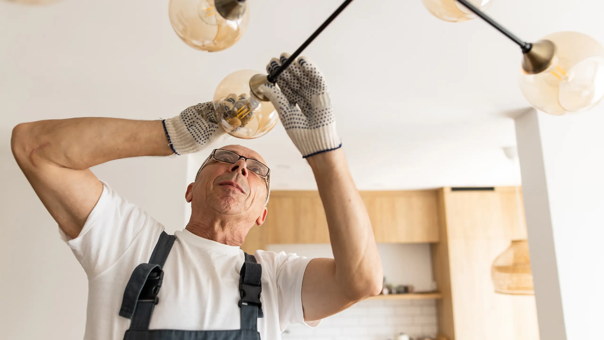A professional male electrician changes a light bulb