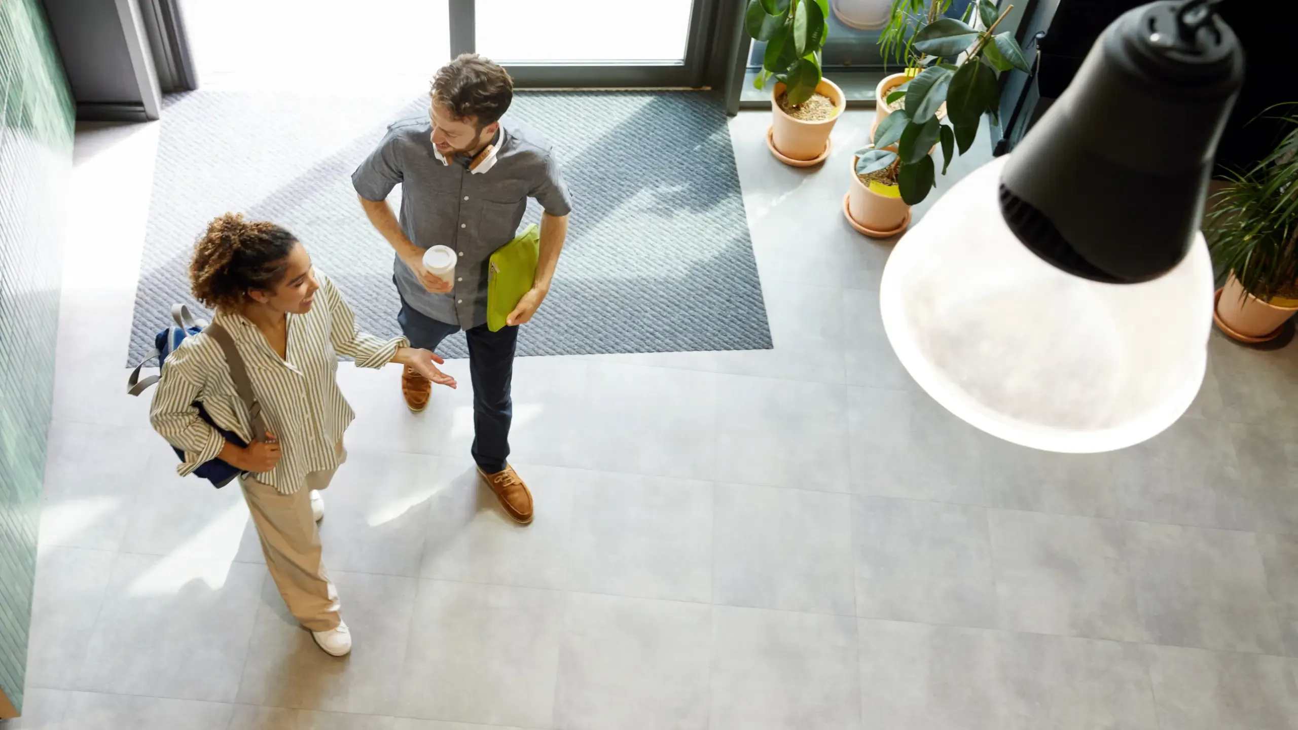 Male and female colleague talking in a modern, sunny office lobby