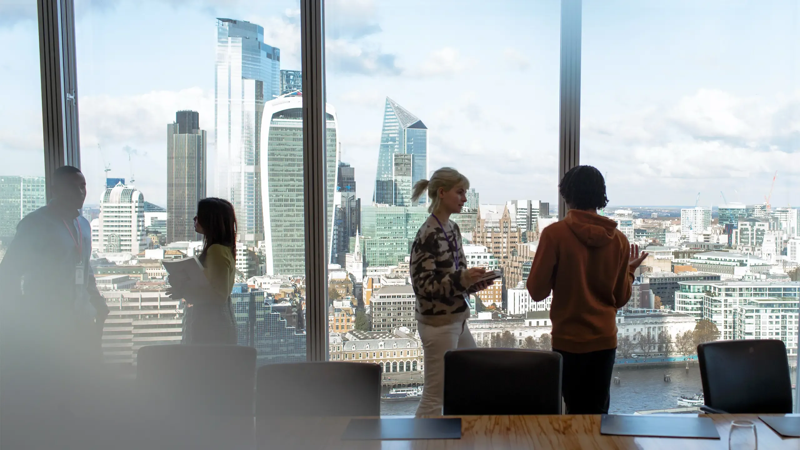Corporate business people talking at highrise office window with city view, London, UK