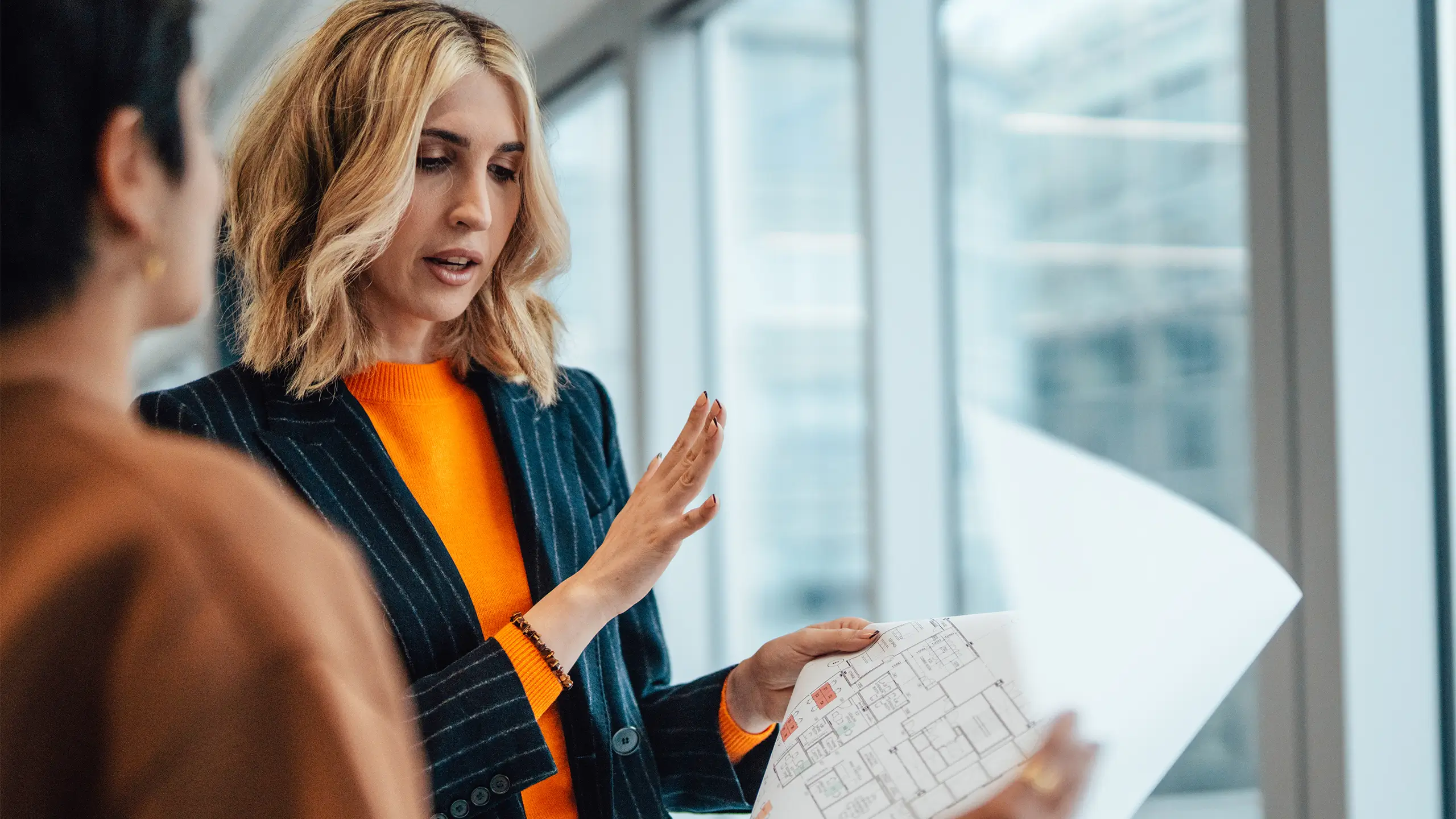 businesswoman having a discussion with her colleague over the floor plan of an empty office space
