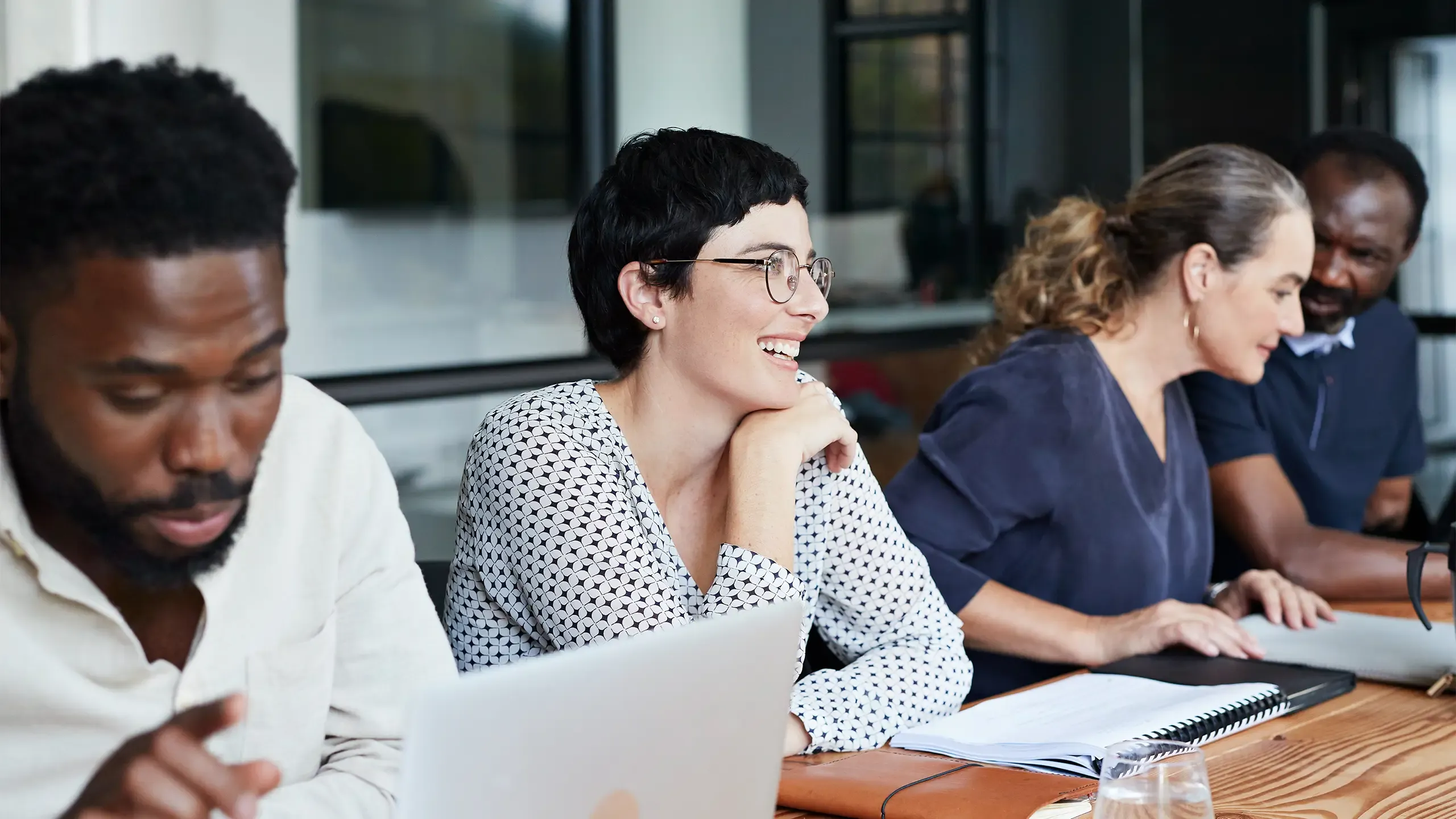 Smiling businesswoman sitting with male and female colleagues in meeting at new workplace