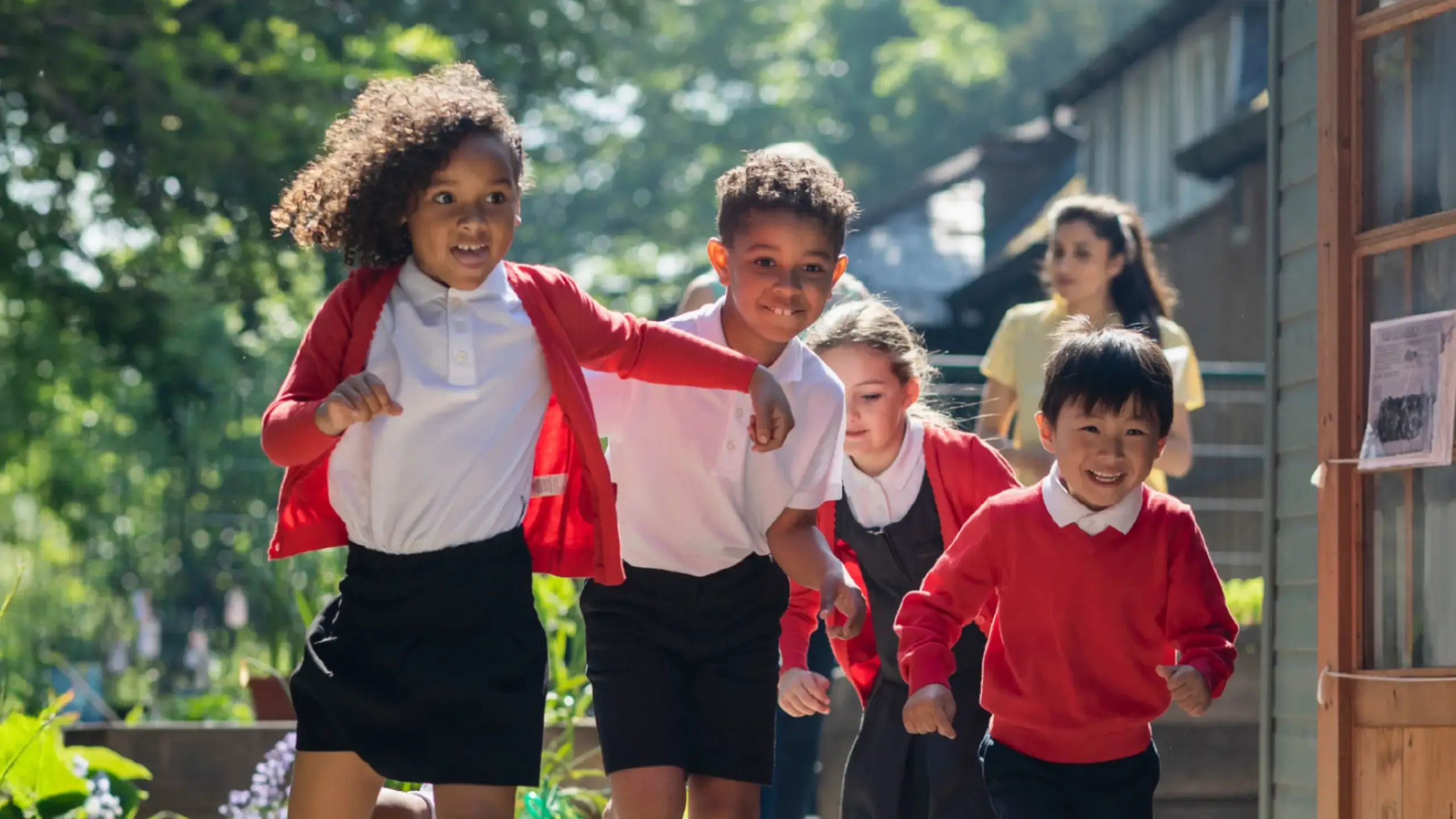 A medium close-up of a group of school children running in the school yard as they head to playtime. 