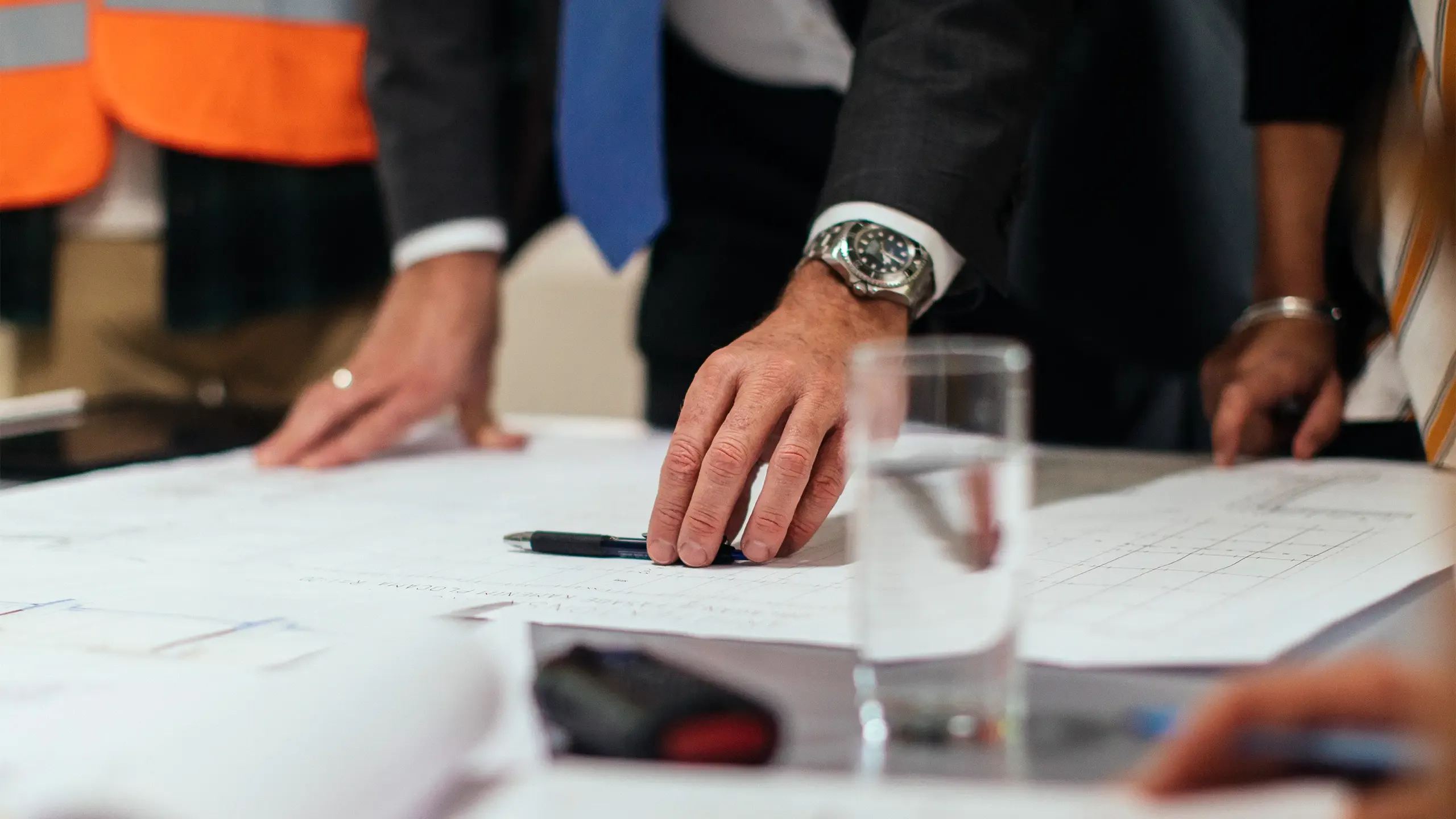 Unrecognisable investors and construction workers discussing architectural plans in the office together