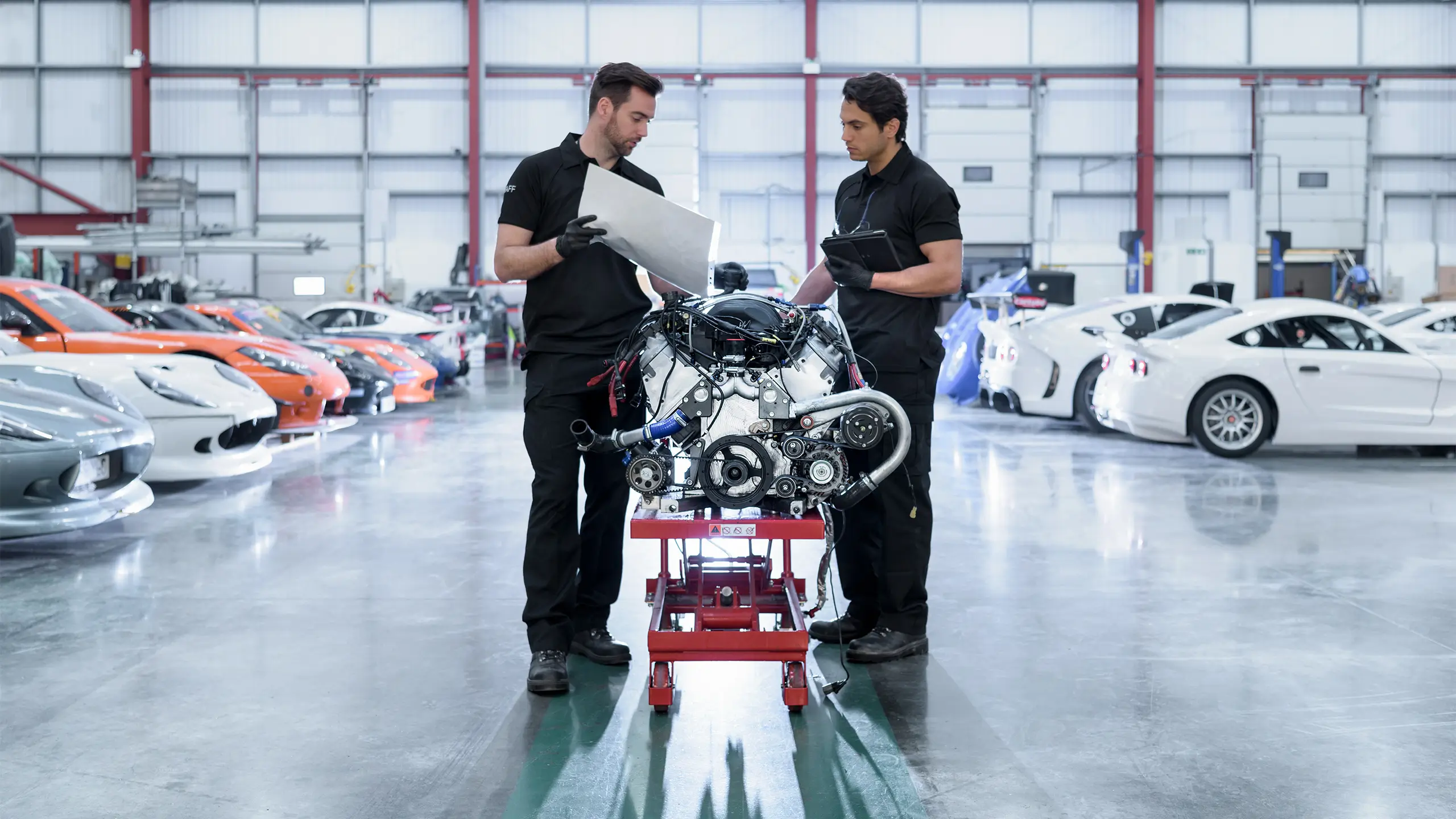 Engineers with engine for repair in racing car factory