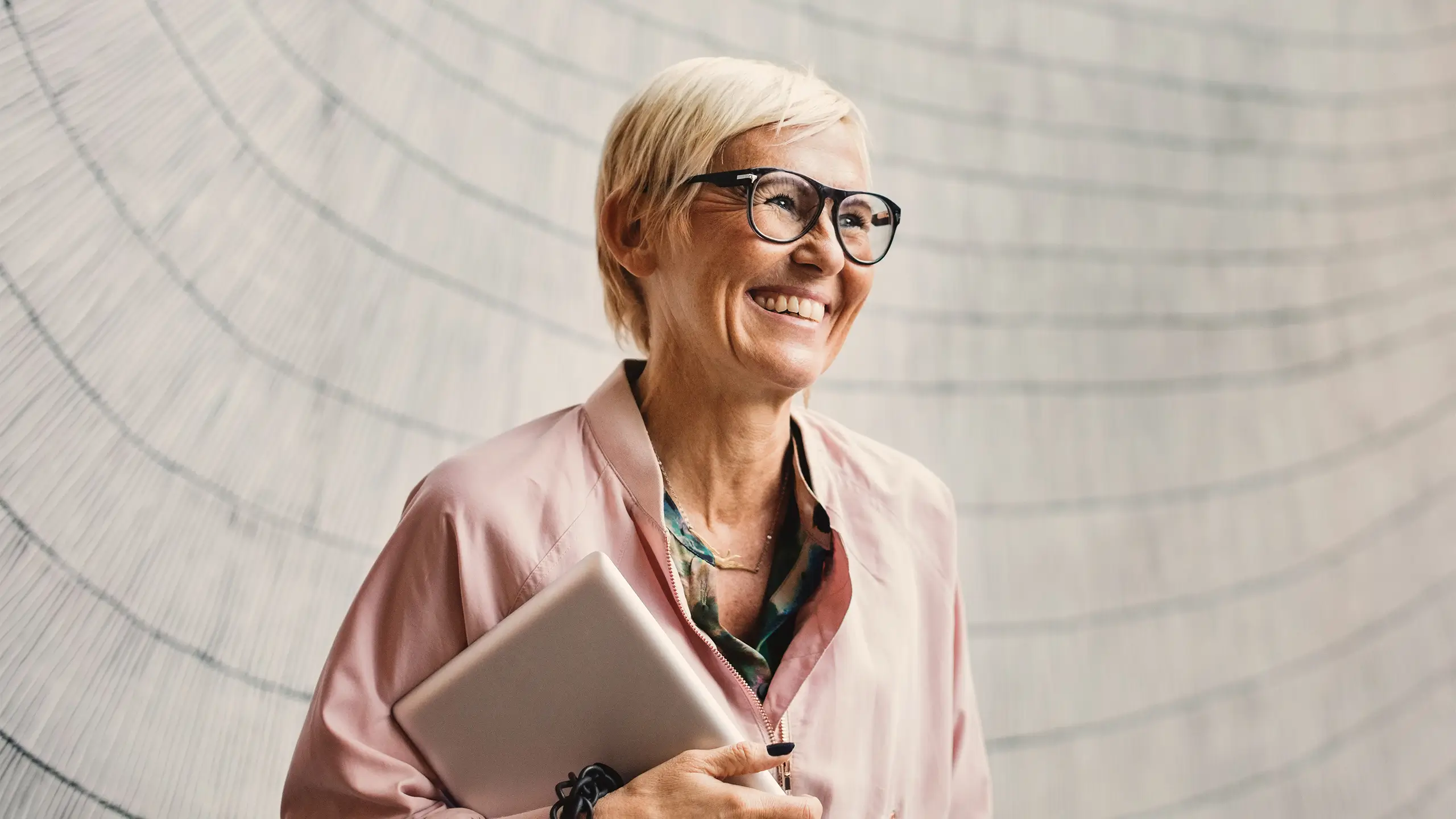 Happy businesswoman holding digital tablet against wall in creative office