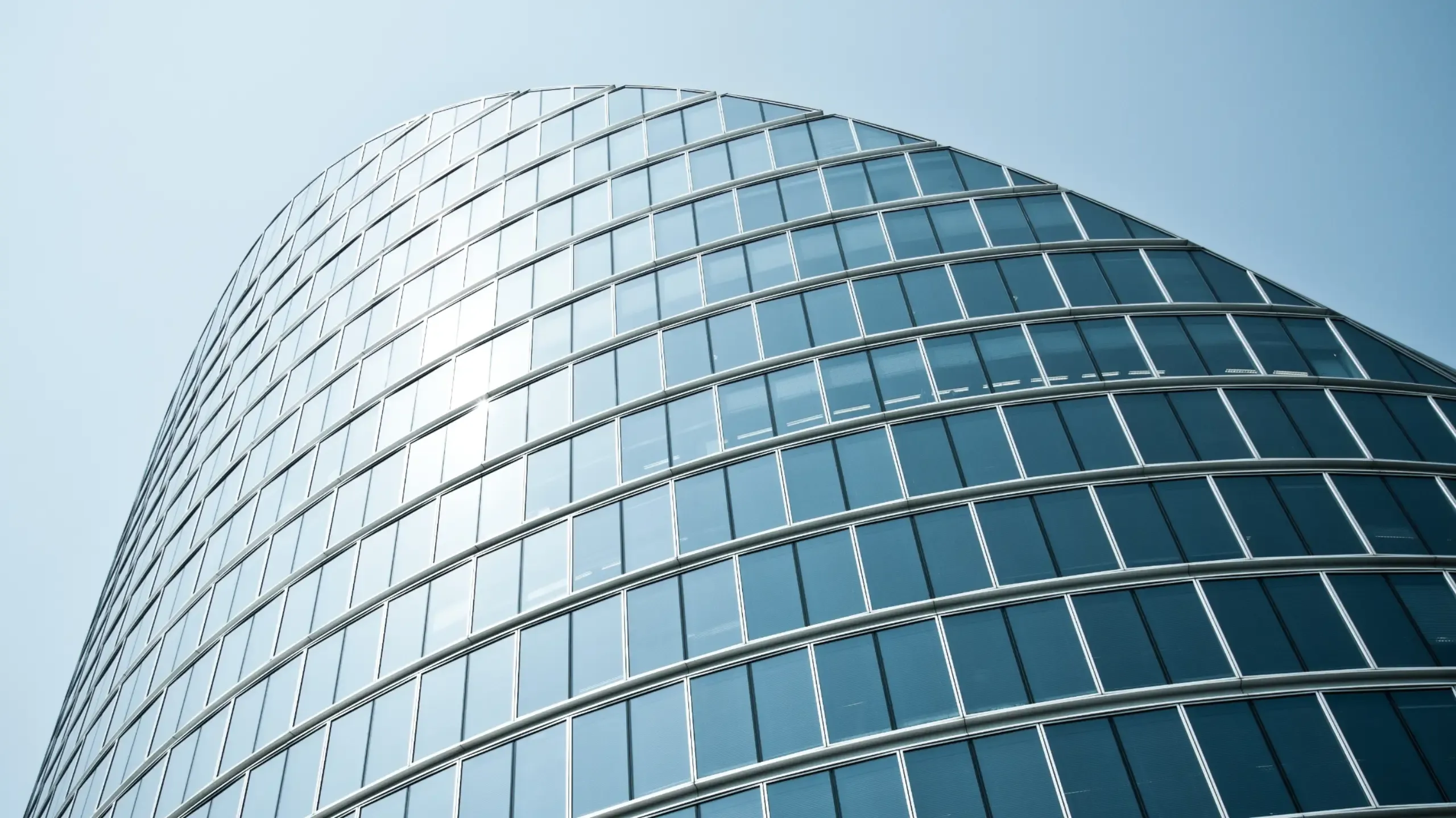 A curved, modern office building against a blue sunny sky