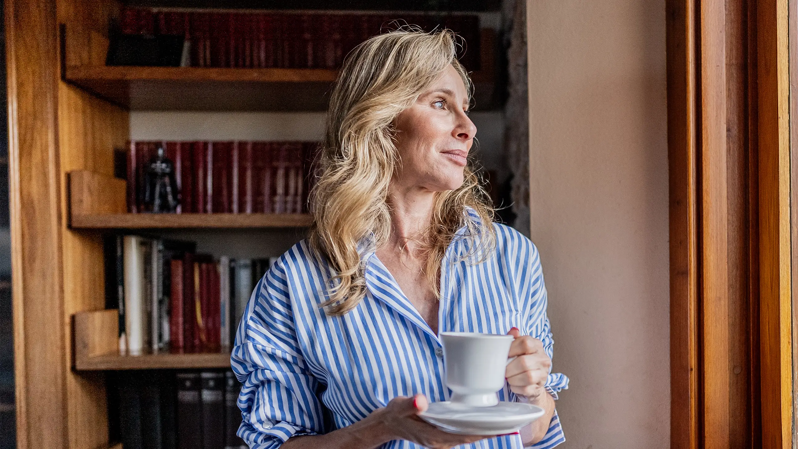 Mature woman contemplating while looking through the window at home