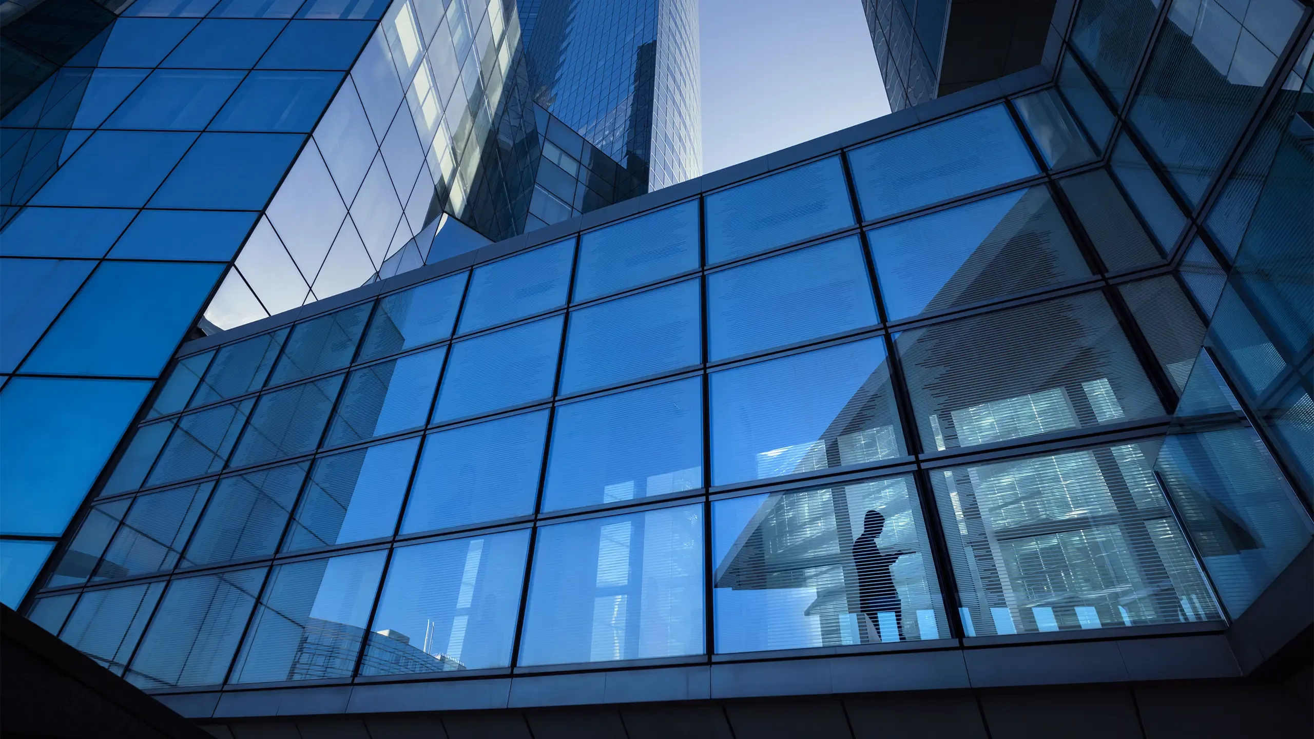 Modern office buildings with silhouette of businessman crossing elevated overpass