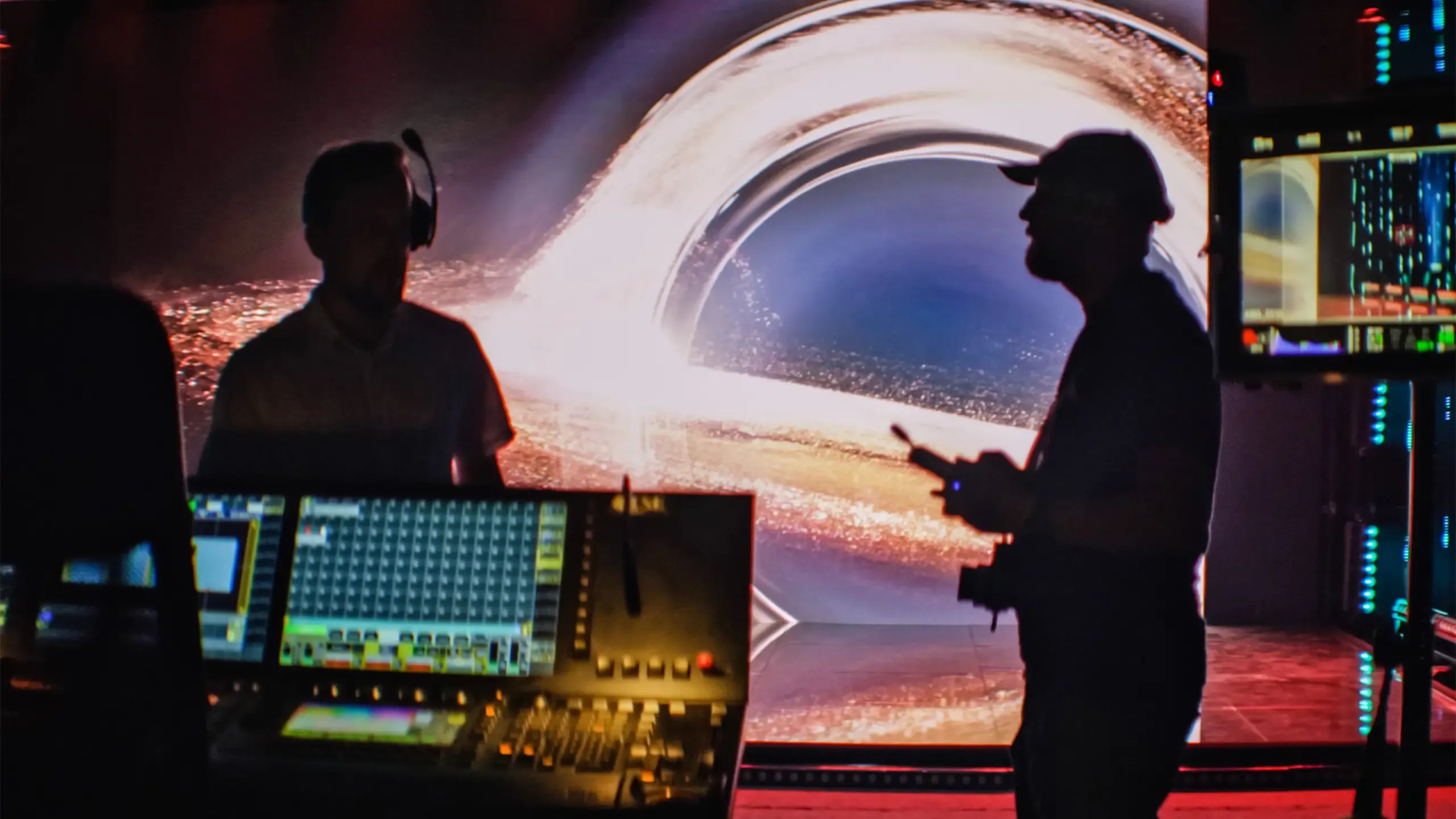 Unrecognisable people working on movie set in foreground. Cameraman, director and assistants silhouettes. Black hole projection