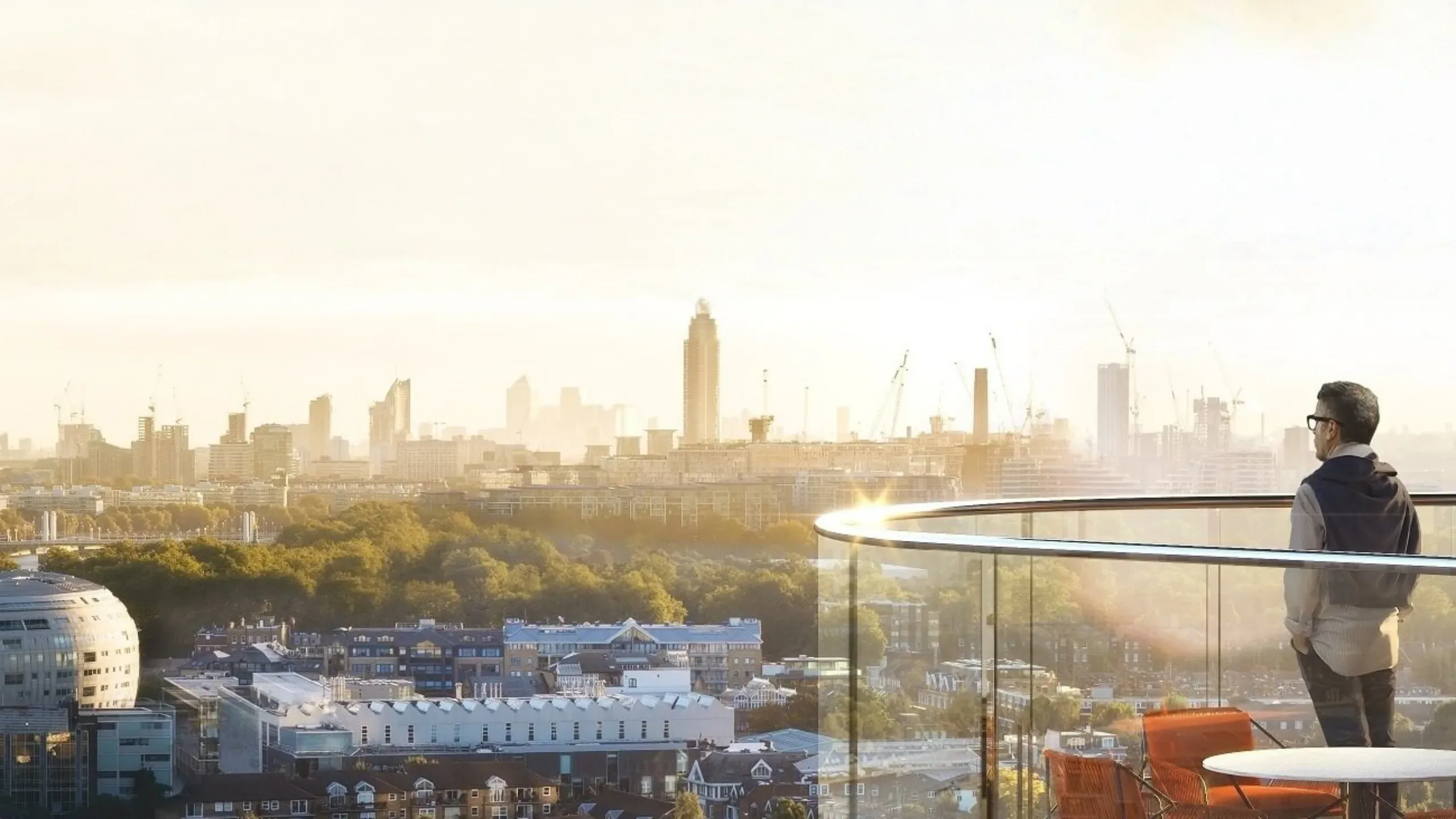 Man looking from his high balcony over the London skyline and Thames River
