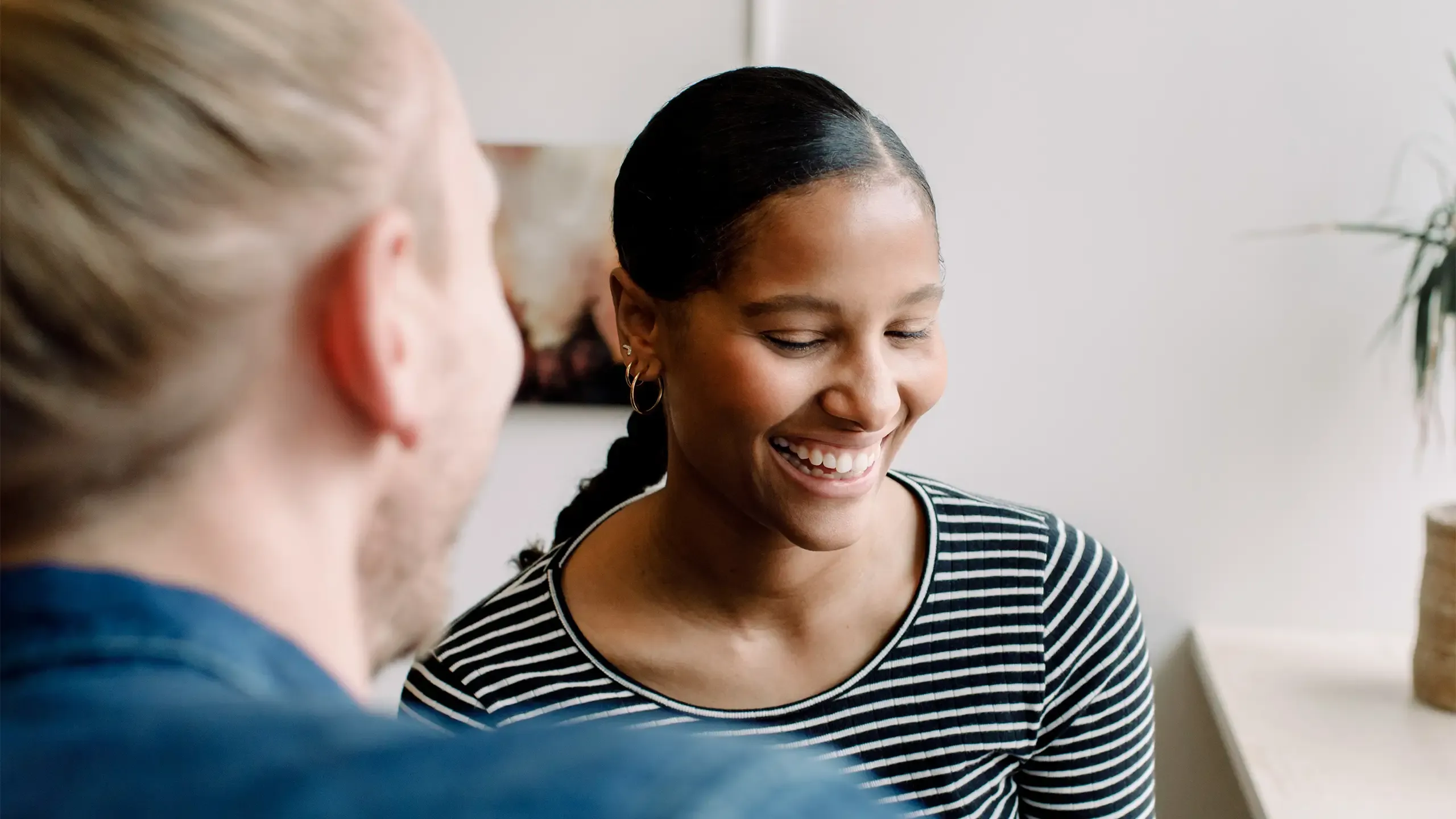 Smiling businesswoman looking at camera while sitting with colleague by desk in office